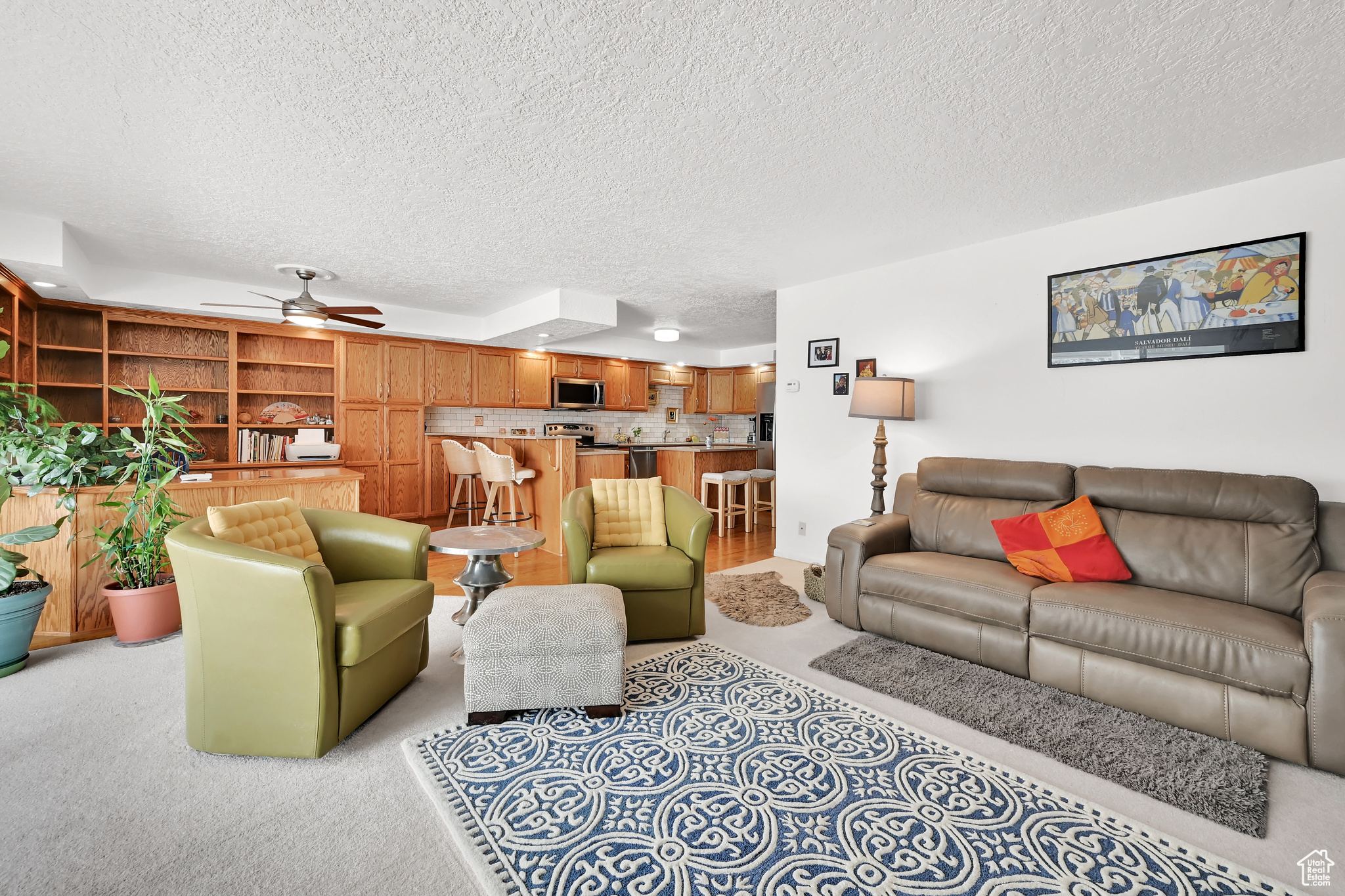 Living area featuring light carpet, ceiling fan, and a textured ceiling