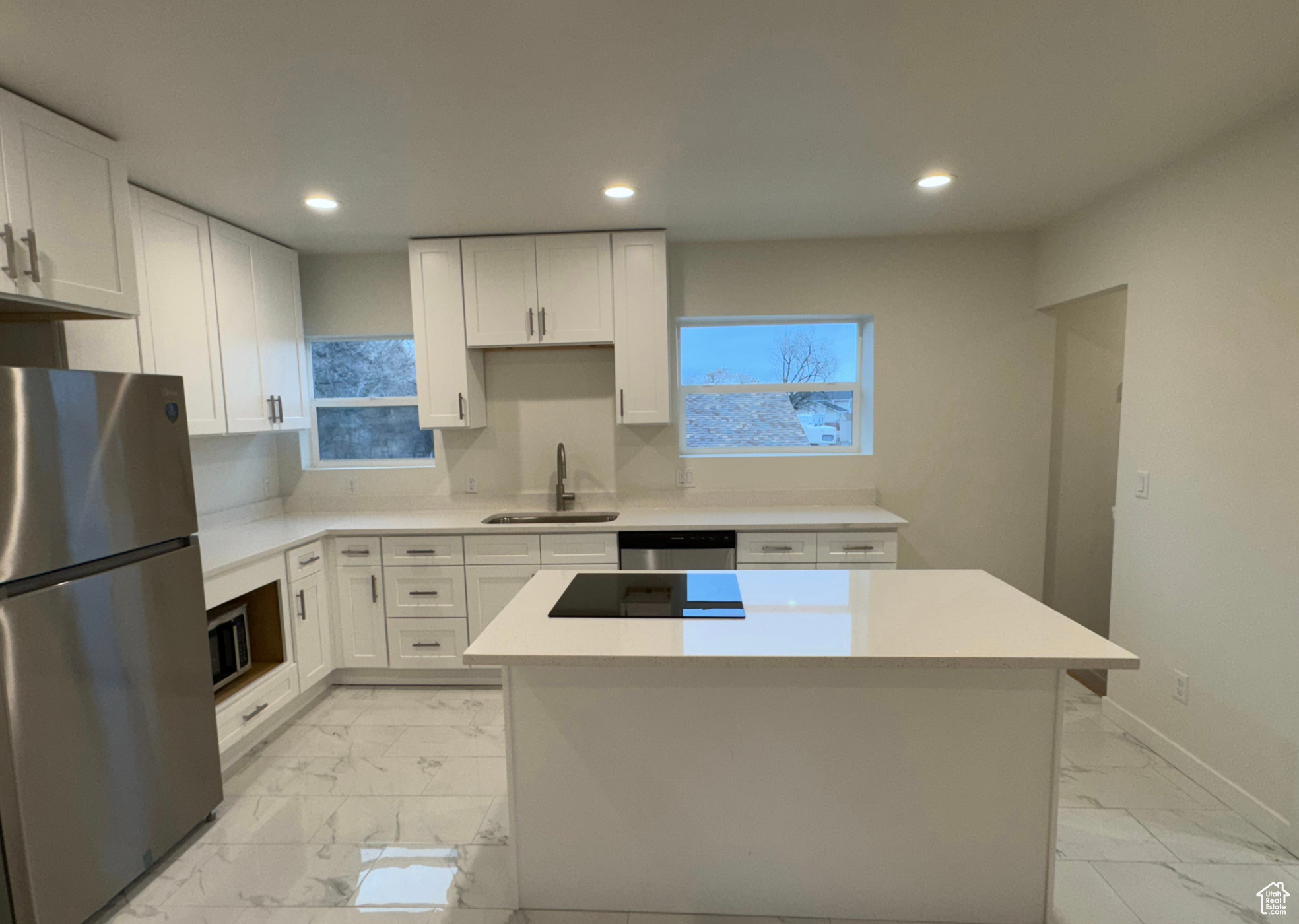 Kitchen with a center island, marble finish floor, stainless steel appliances, light countertops, and white cabinetry