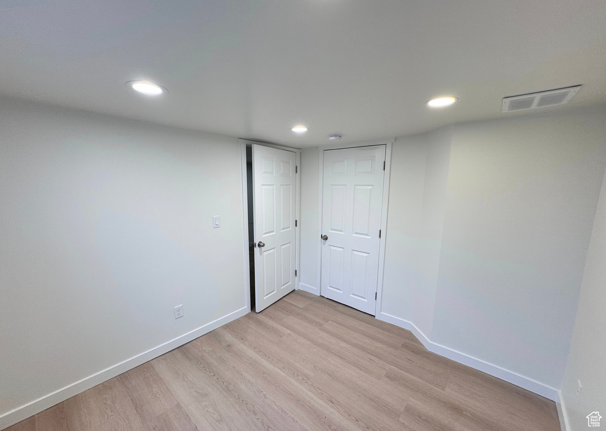 Empty room featuring light wood-type flooring, visible vents, baseboards, and recessed lighting