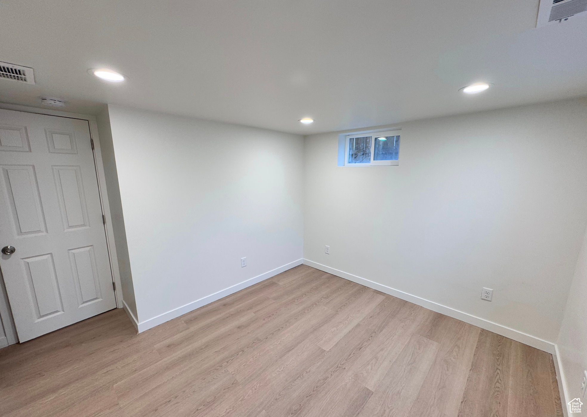 Basement featuring light wood finished floors, visible vents, and baseboards