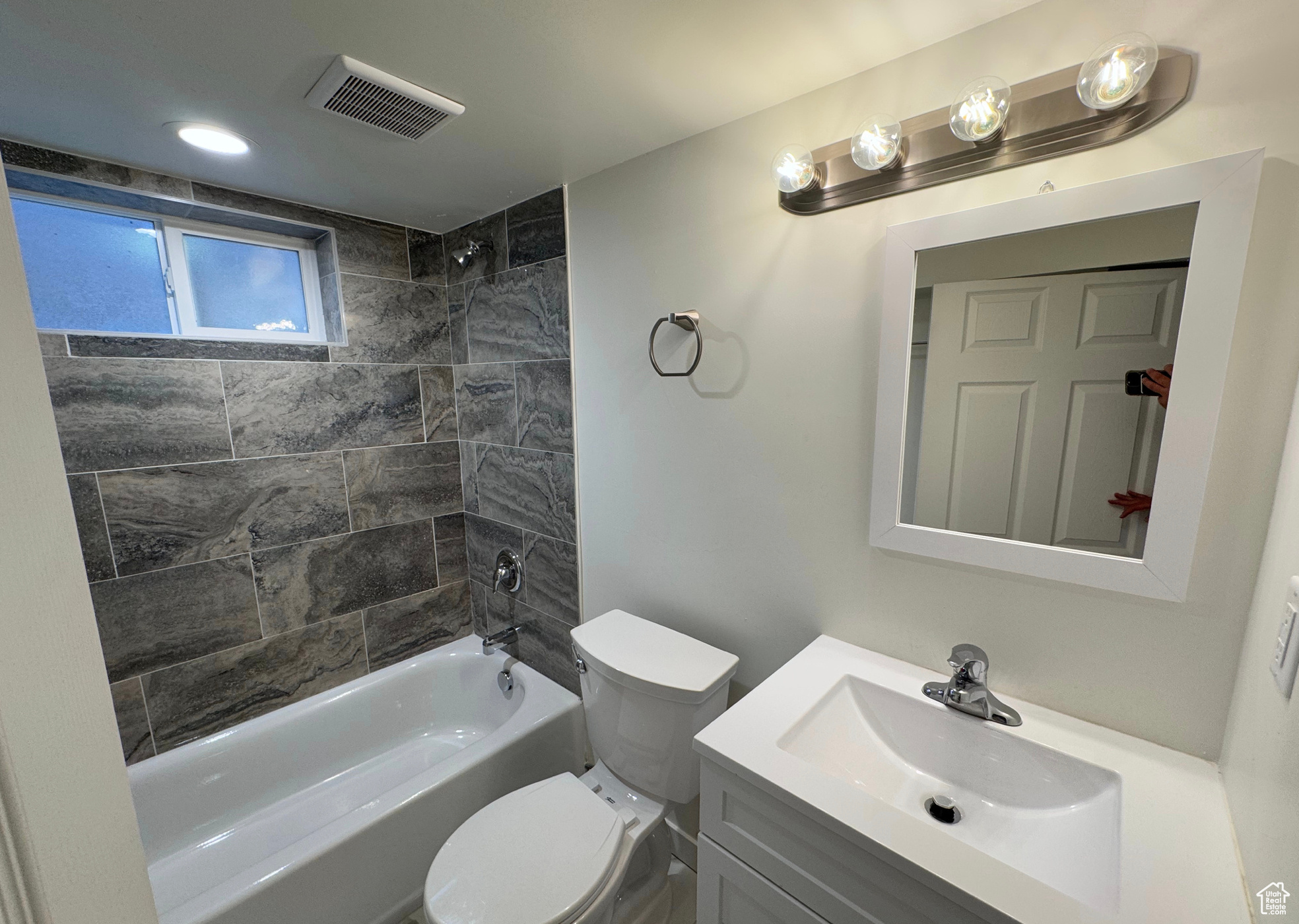 Bathroom featuring toilet, vanity, visible vents, and shower / bathing tub combination
