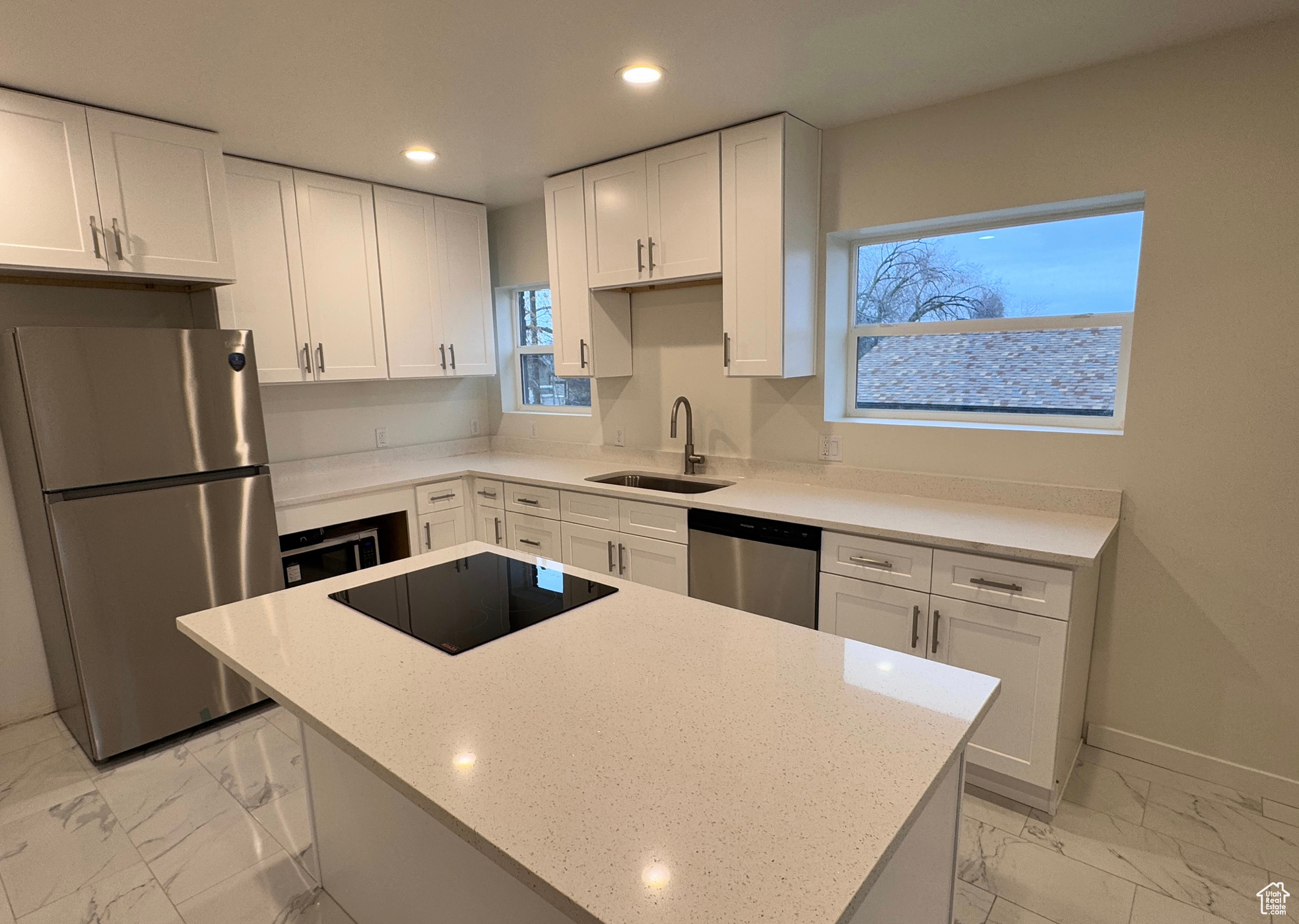 Kitchen featuring white cabinets, light stone counters, marble finish floor, stainless steel appliances, and a sink