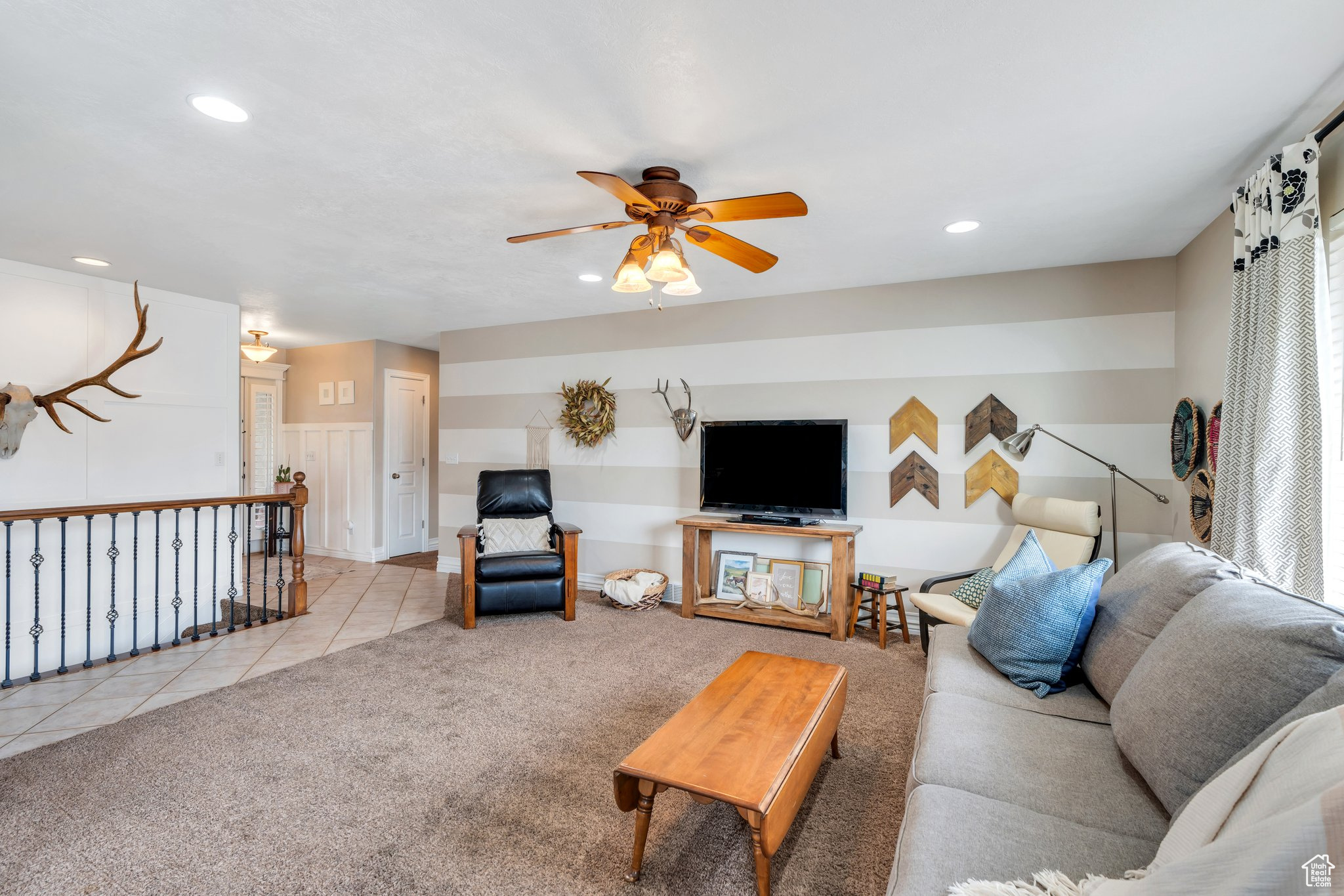 Living area with recessed lighting, wainscoting, light carpet, ceiling fan, and light tile patterned flooring