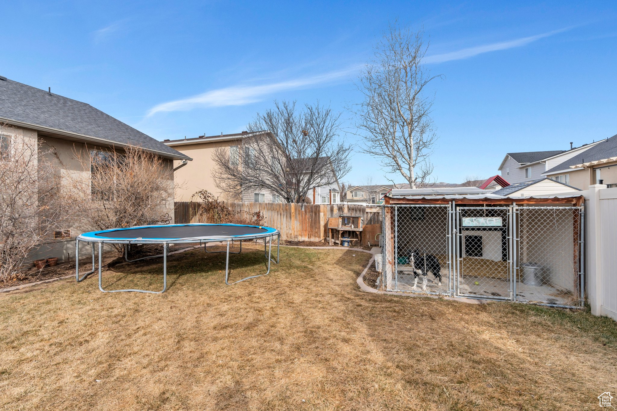 View of yard featuring a trampoline, fence, an exterior structure, and an outdoor structure