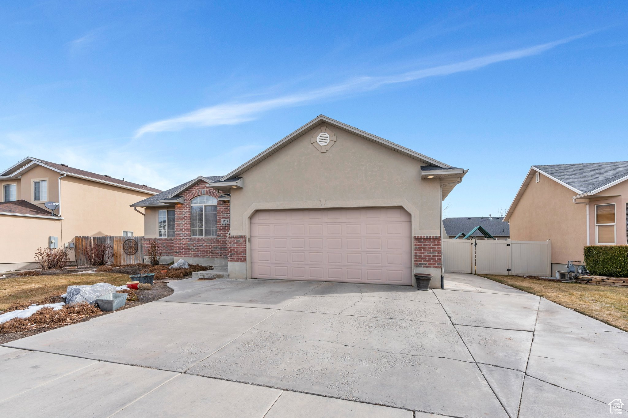 View of front of house featuring brick siding, concrete driveway, an attached garage, a gate, and stucco siding