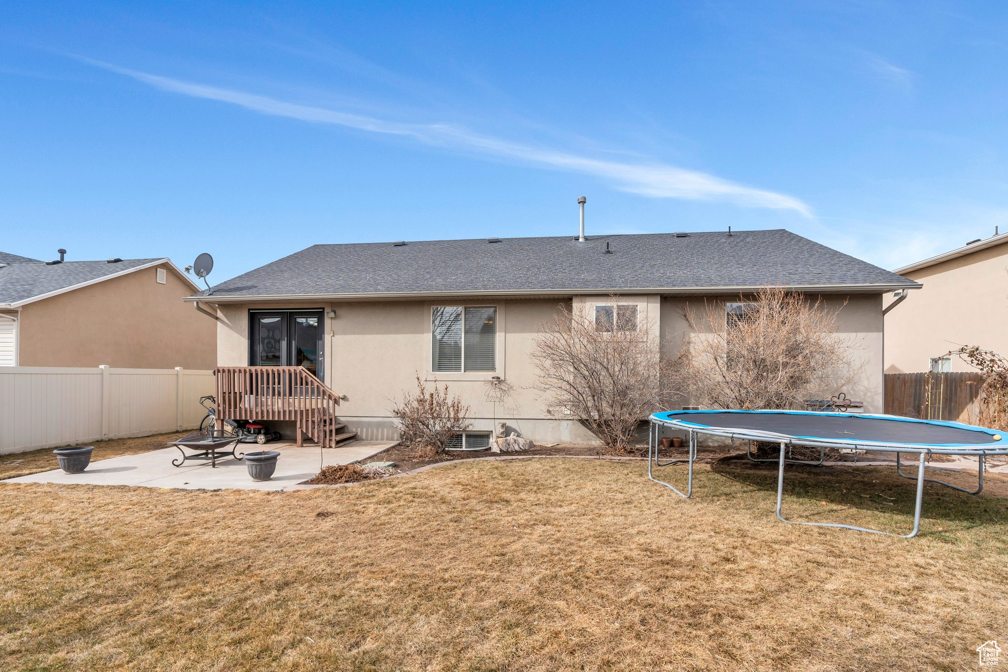 Back of house with a fenced backyard, a yard, stucco siding, a trampoline, and a patio area
