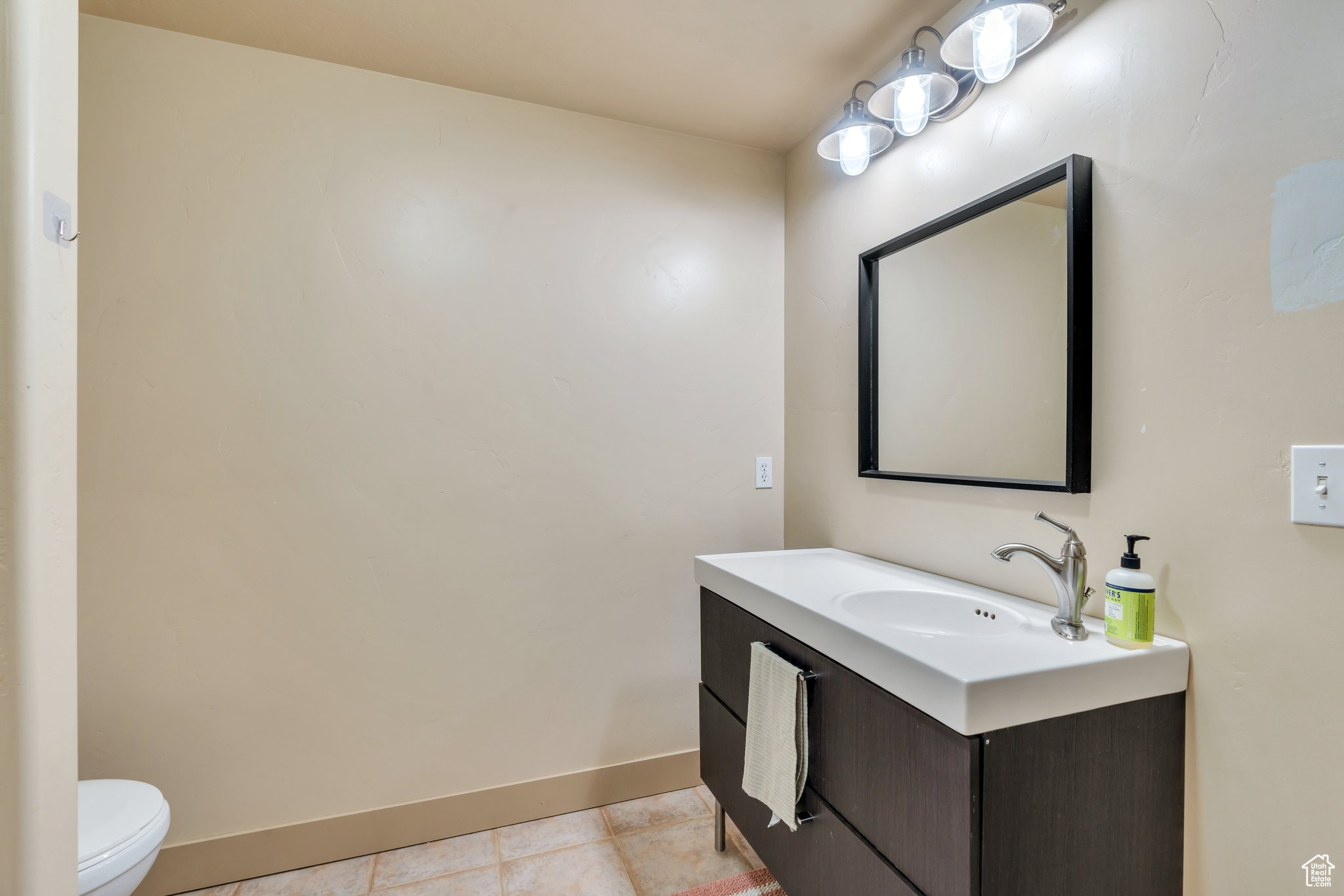 Bathroom featuring toilet, vanity, baseboards, and tile patterned floors