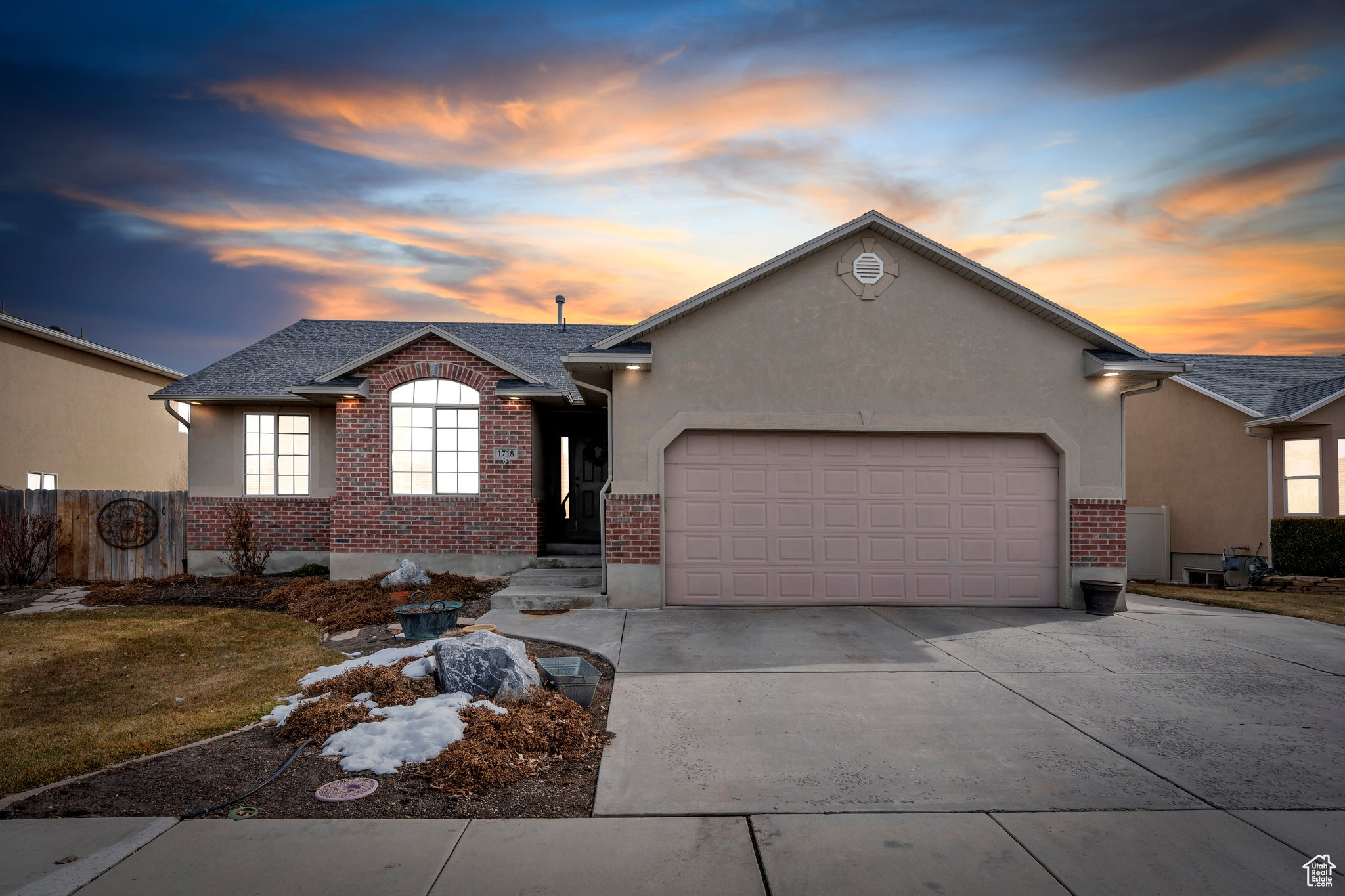 Ranch-style home featuring an attached garage, brick siding, a shingled roof, driveway, and stucco siding