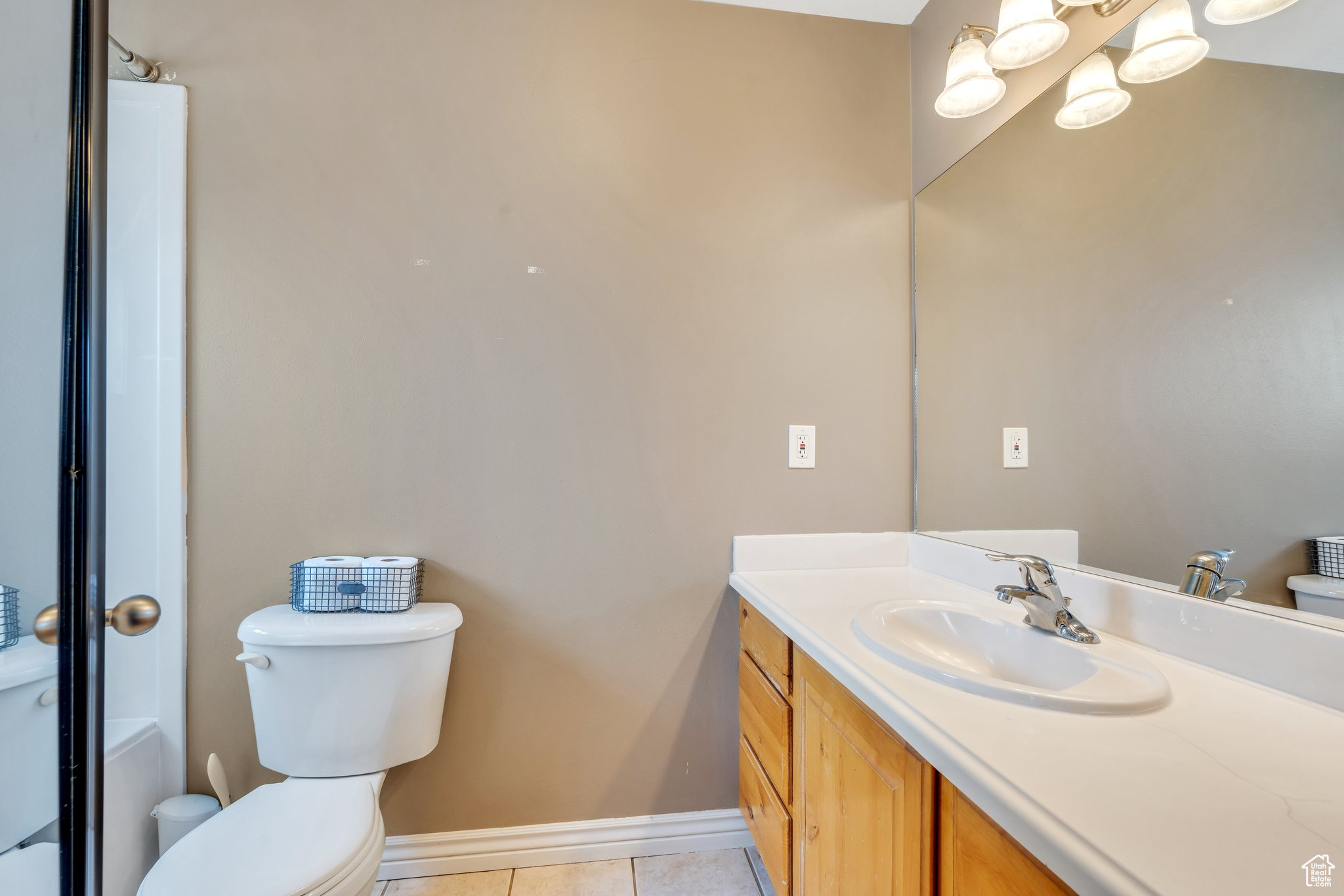 Bathroom featuring toilet, a notable chandelier, vanity, baseboards, and tile patterned floors