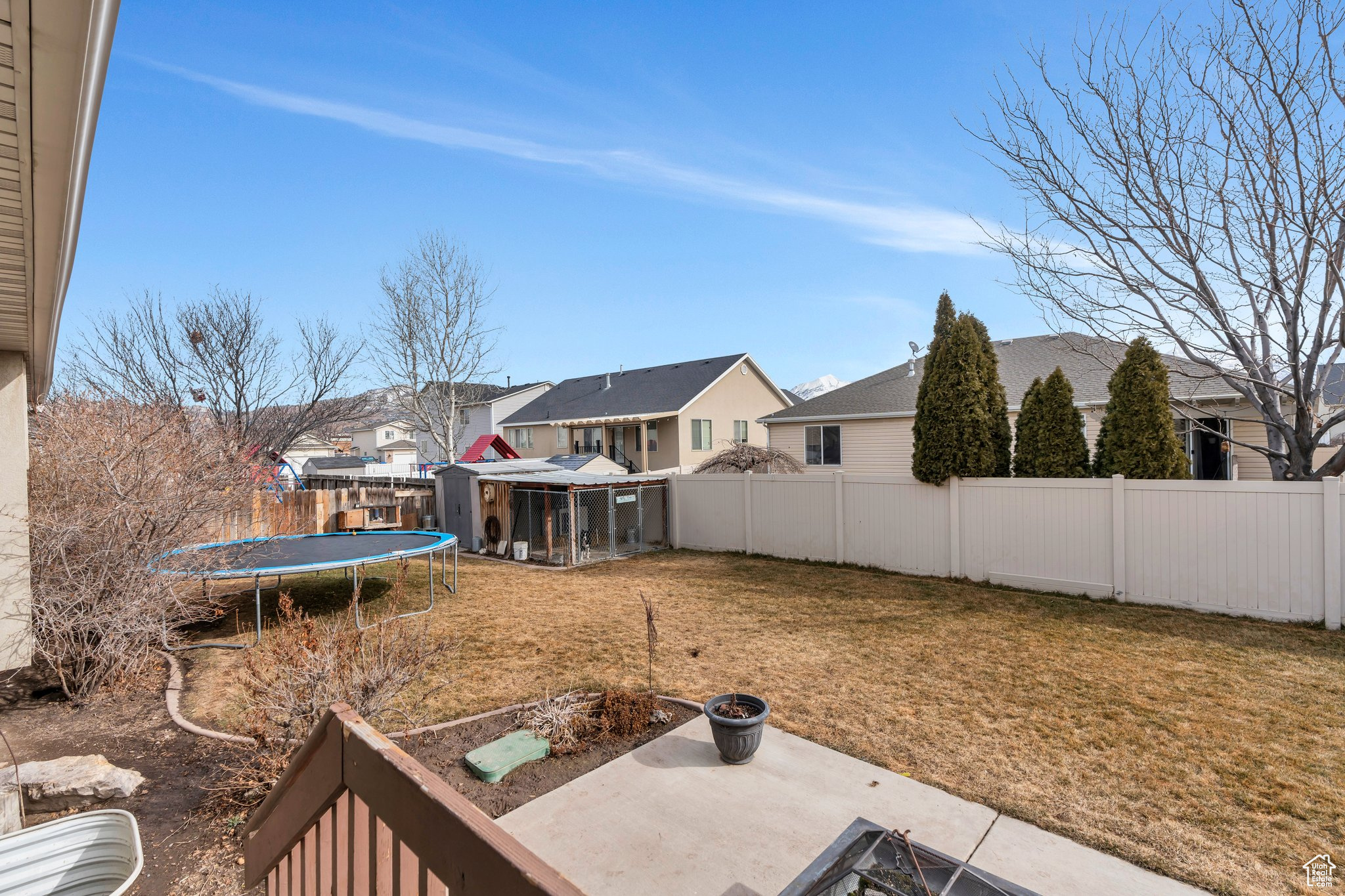 View of yard featuring a trampoline, a patio area, a fenced backyard, and a residential view