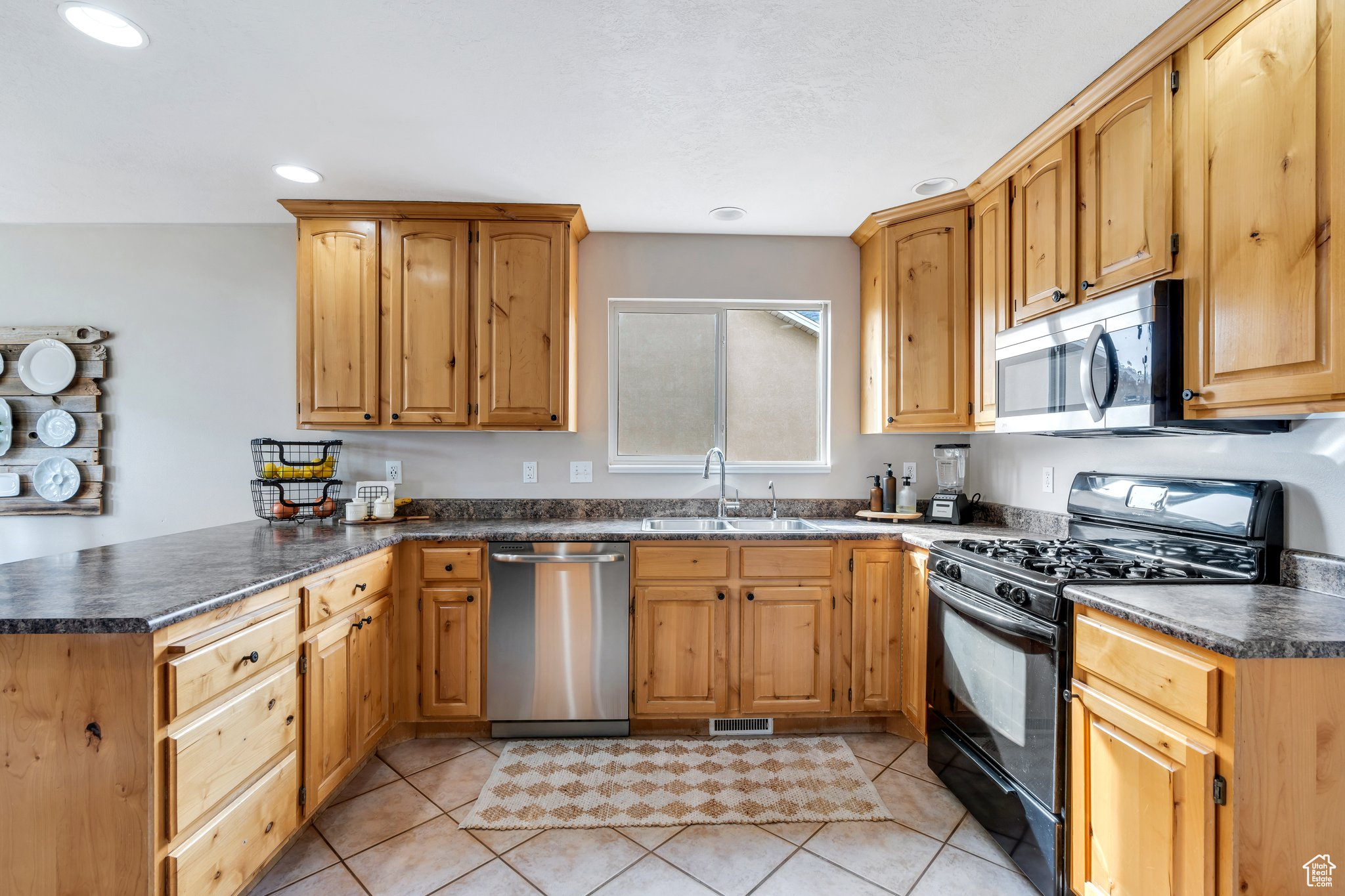 Kitchen featuring stainless steel appliances, dark countertops, a sink, and a peninsula