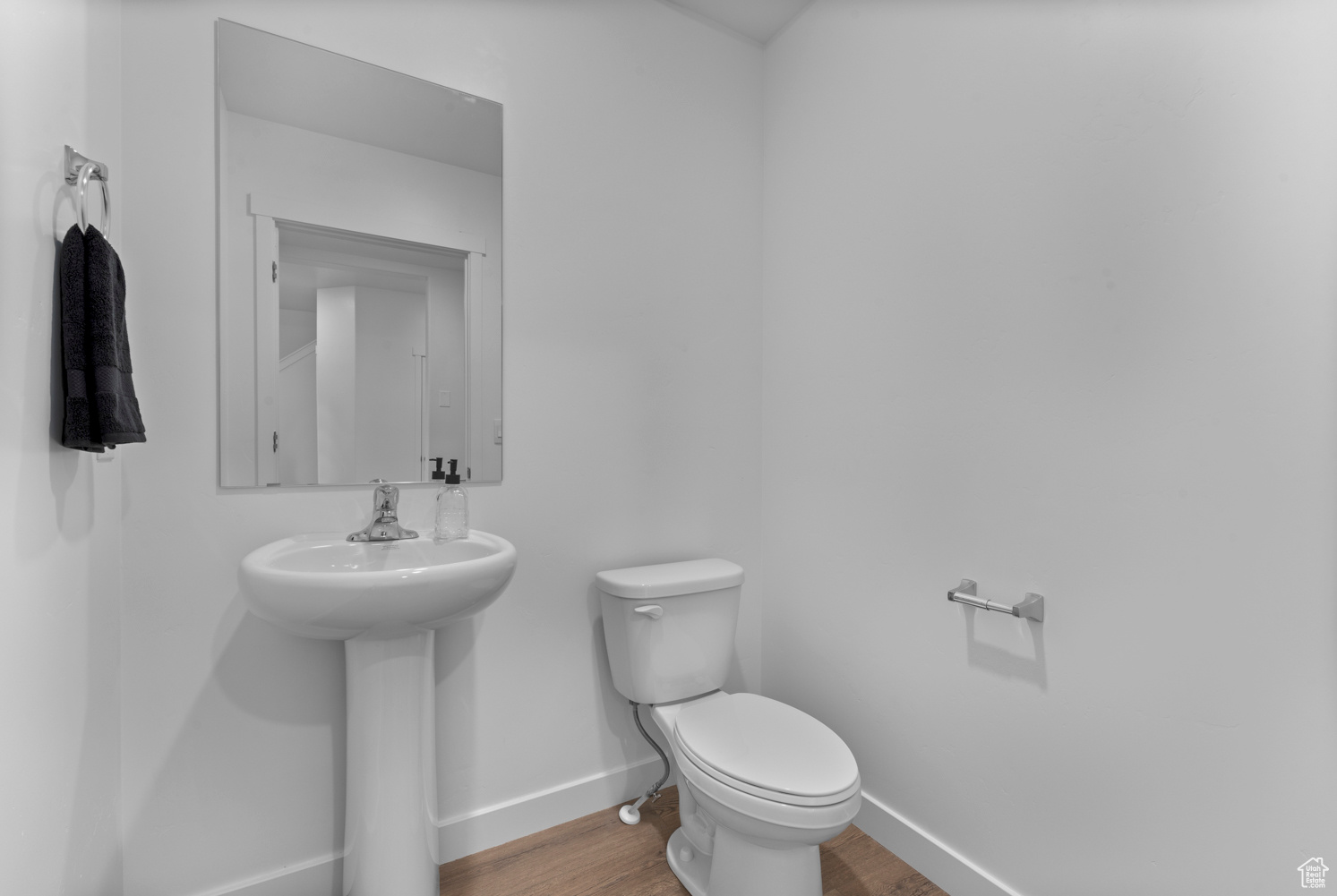 Bathroom featuring a sink, wood finished floors, toilet, and baseboards