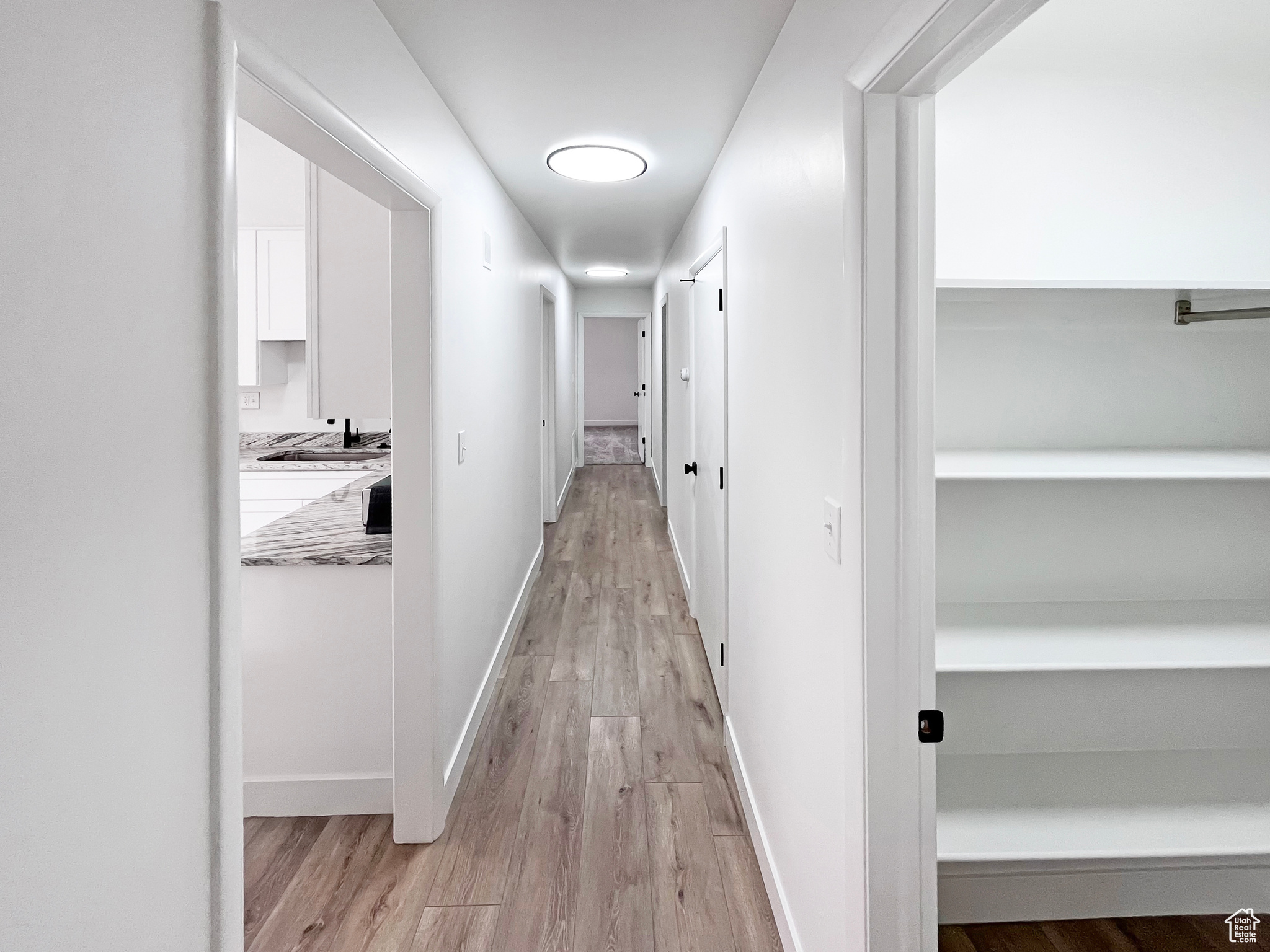 Well-lit hallway featuring tasteful colors and light wood-style floors