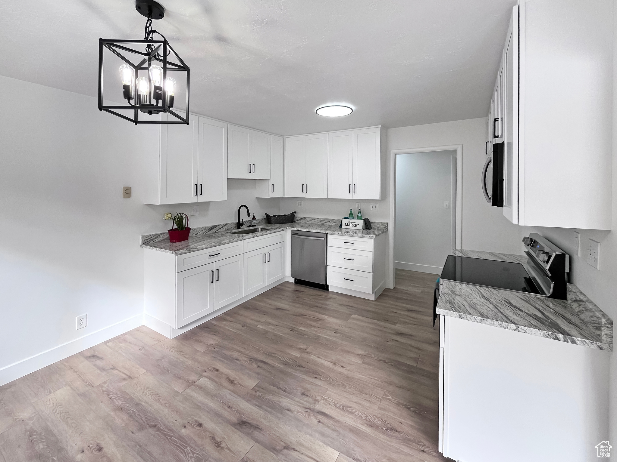 Beautifully updated kitchen with granite countertops, tall white cabinets, light wood-style flooring and stainless-steel appliances, and ample natural light