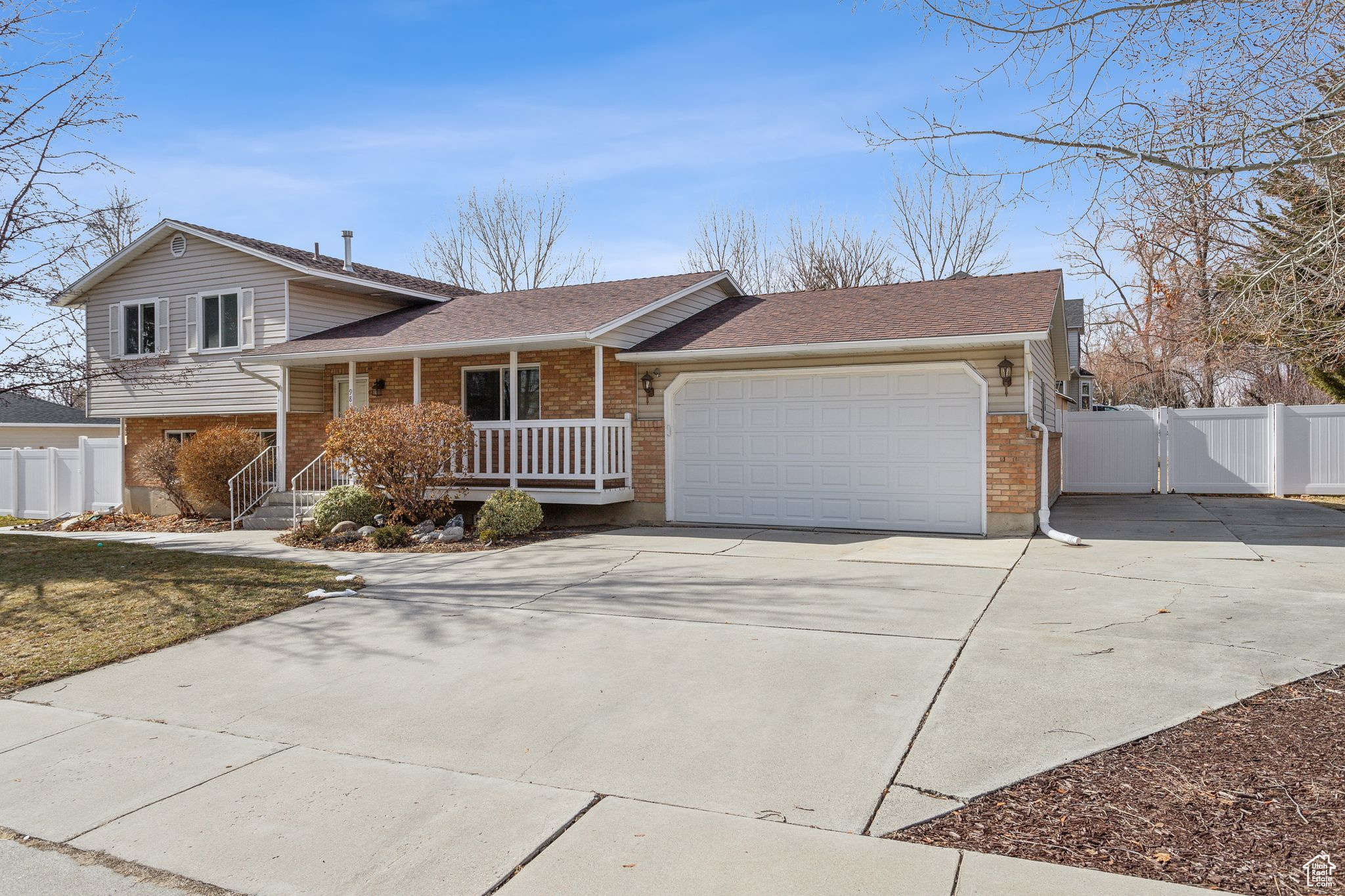 Tri-level home with an attached garage, covered porch, concrete driveway, and brick siding