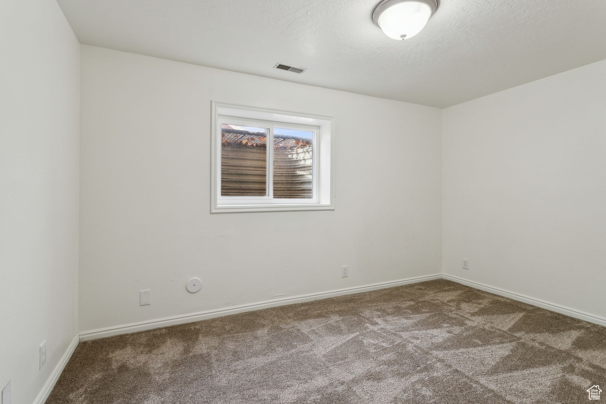 Unfurnished room featuring carpet, a textured ceiling, visible vents, and baseboards