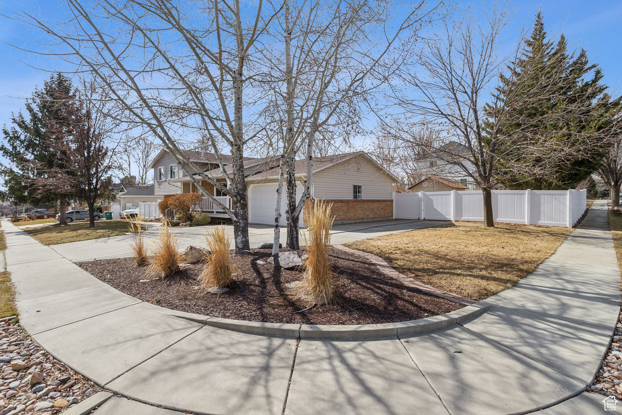 View of front of home featuring driveway, brick siding, fence, and a residential view
