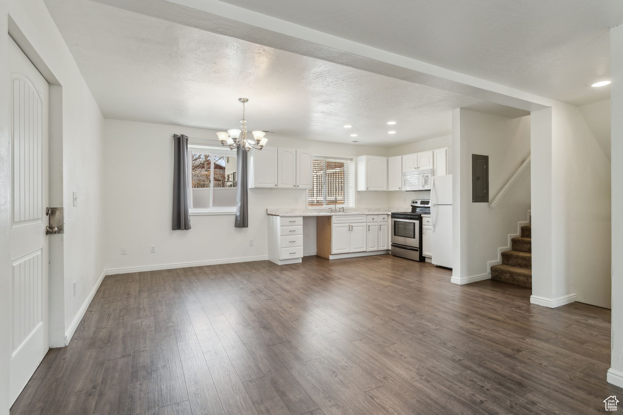 Kitchen with white appliances, white cabinets, dark wood-style floors, decorative light fixtures, and light countertops