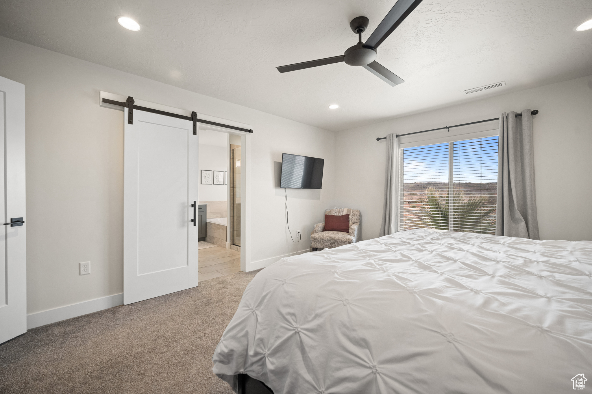 Bedroom with a barn door, carpet flooring, visible vents, and baseboards