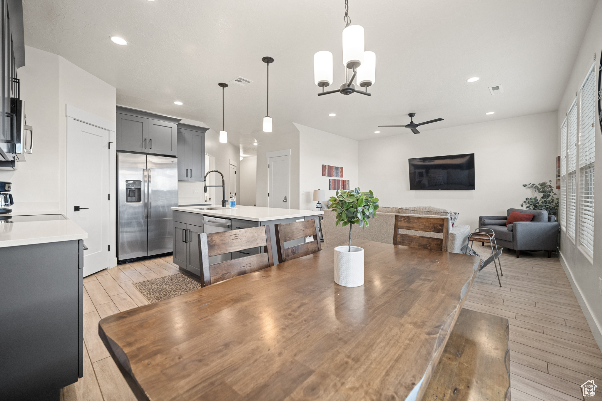 Dining space featuring ceiling fan with notable chandelier, wood tiled floor, visible vents, and recessed lighting