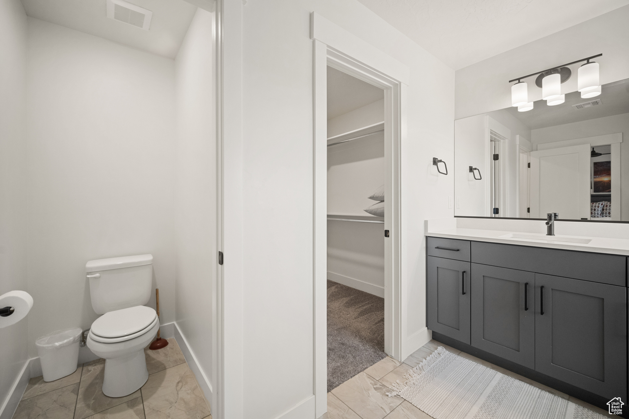 Bathroom with toilet, a spacious closet, vanity, and visible vents