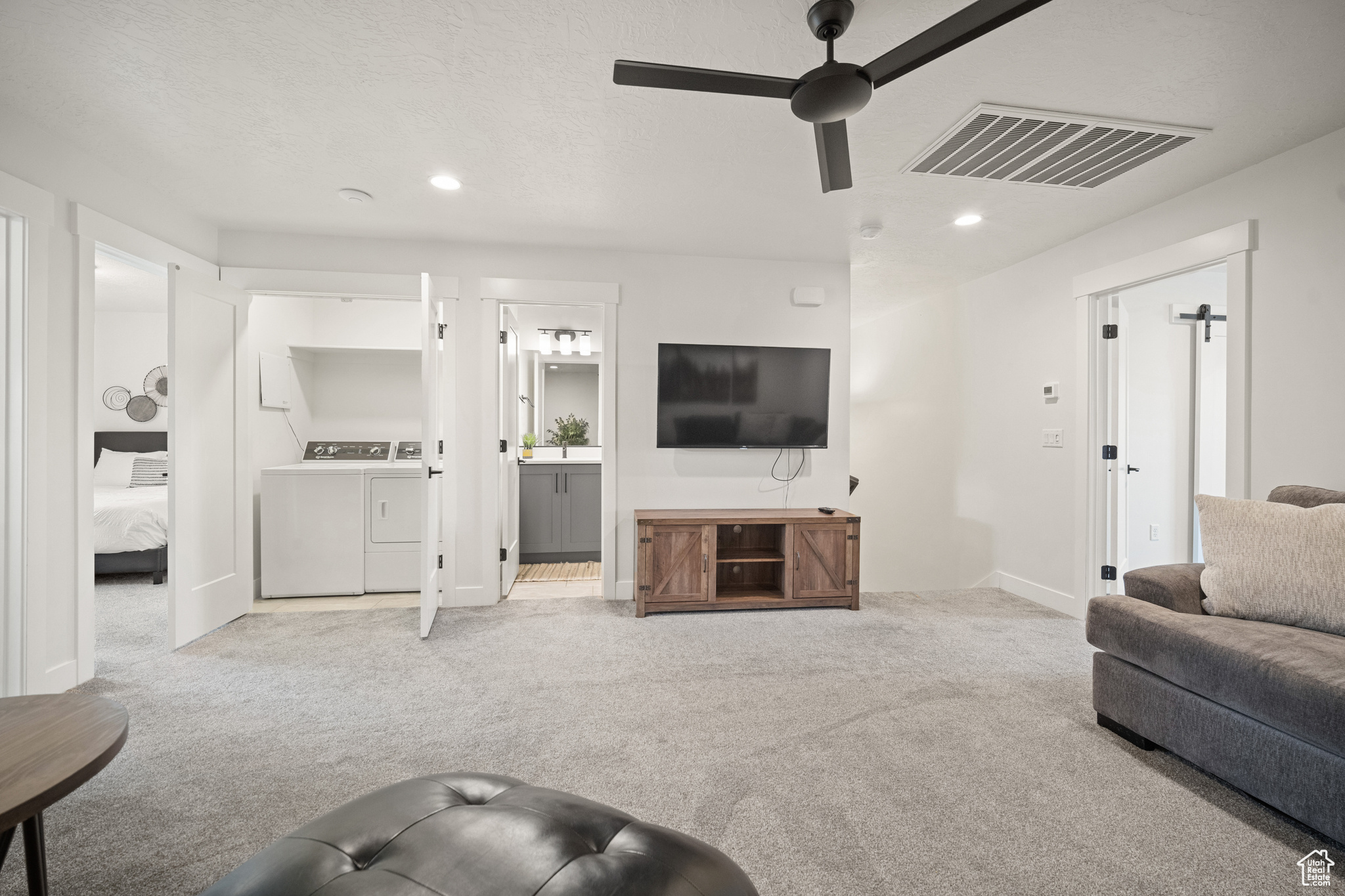 Carpeted living room featuring recessed lighting, visible vents, ceiling fan, and washing machine and clothes dryer