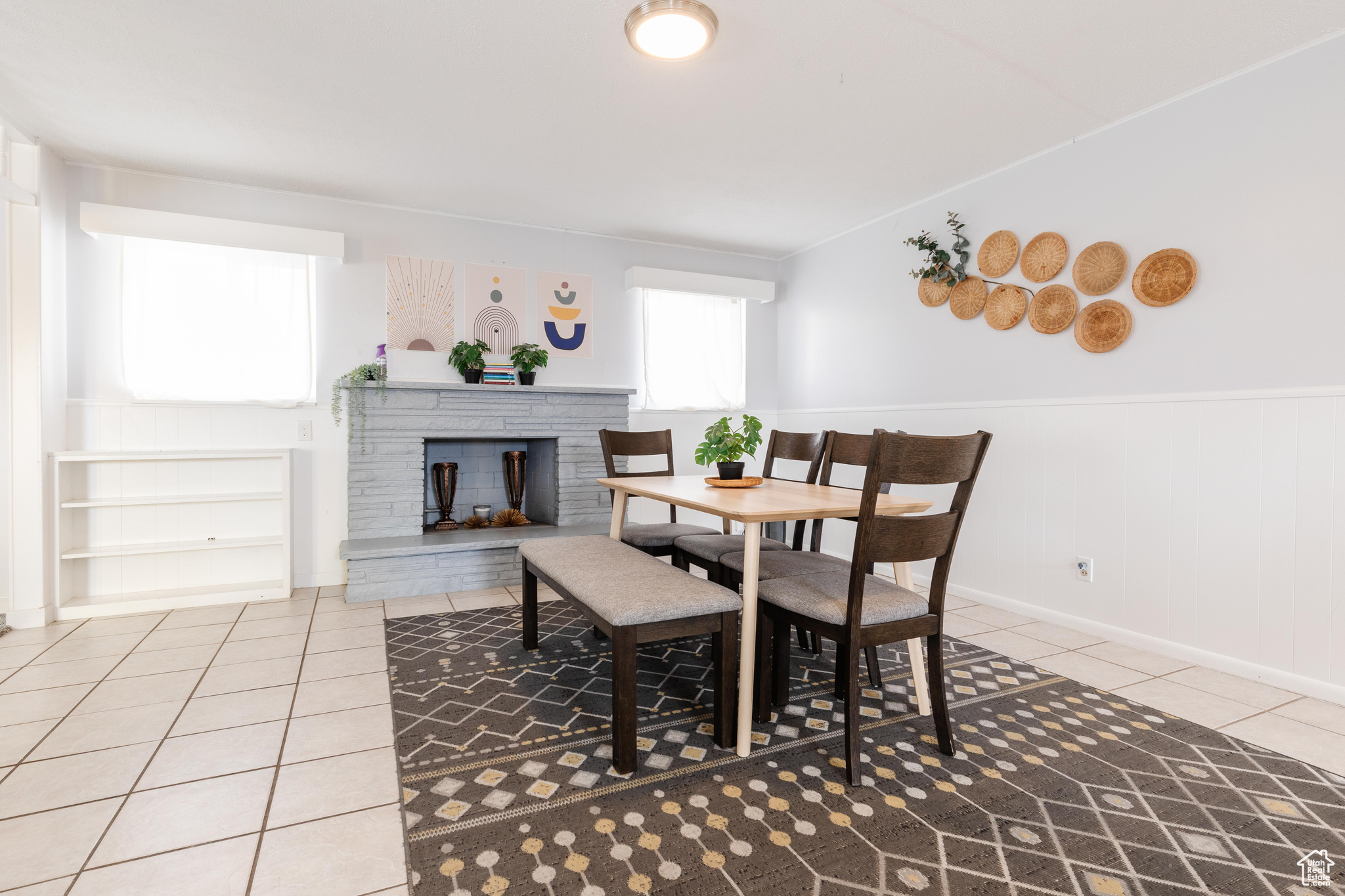 Dining area featuring wainscoting, light tile patterned flooring, and a fireplace