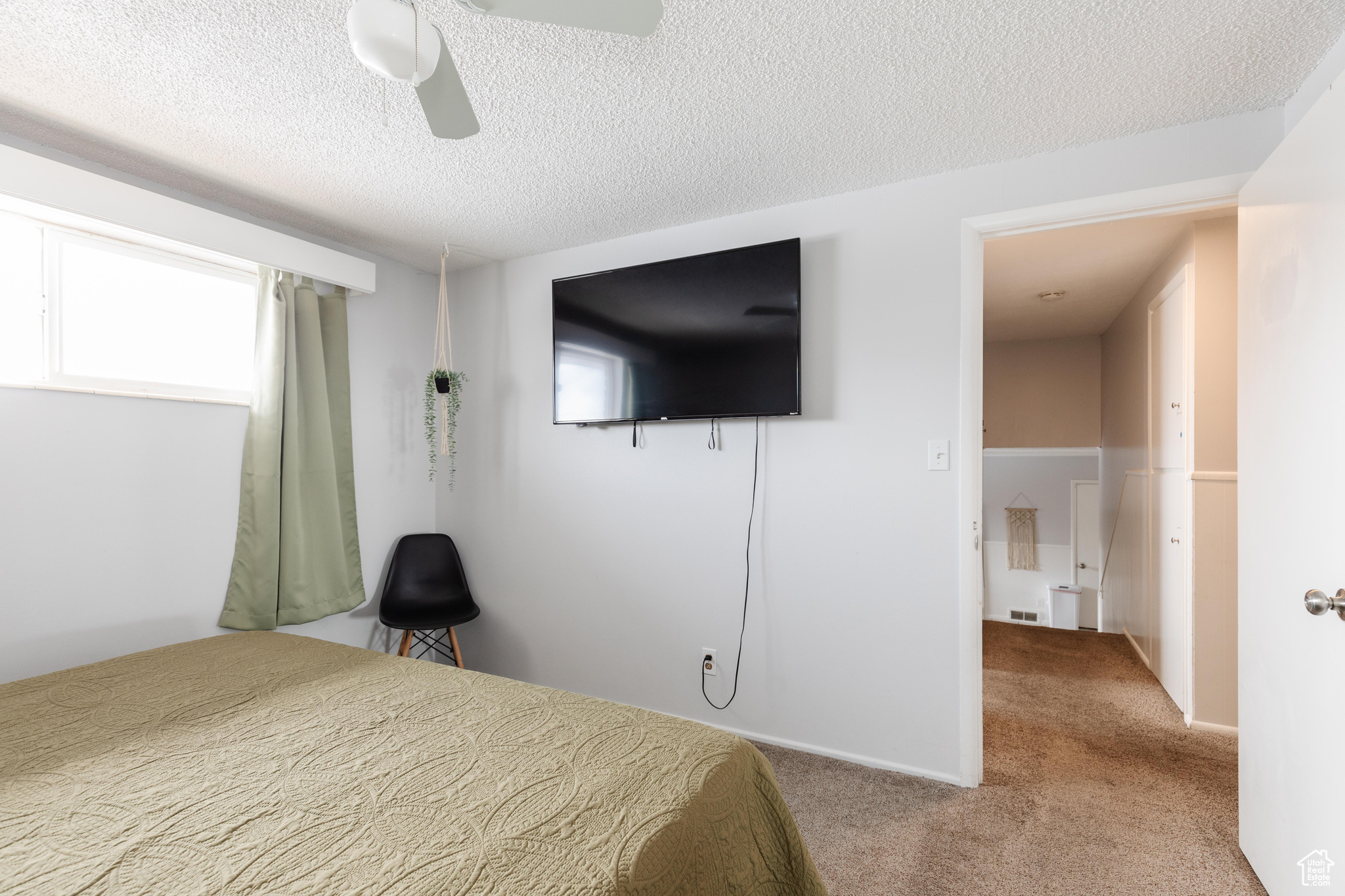 Bedroom featuring light colored carpet, ceiling fan, and a textured ceiling