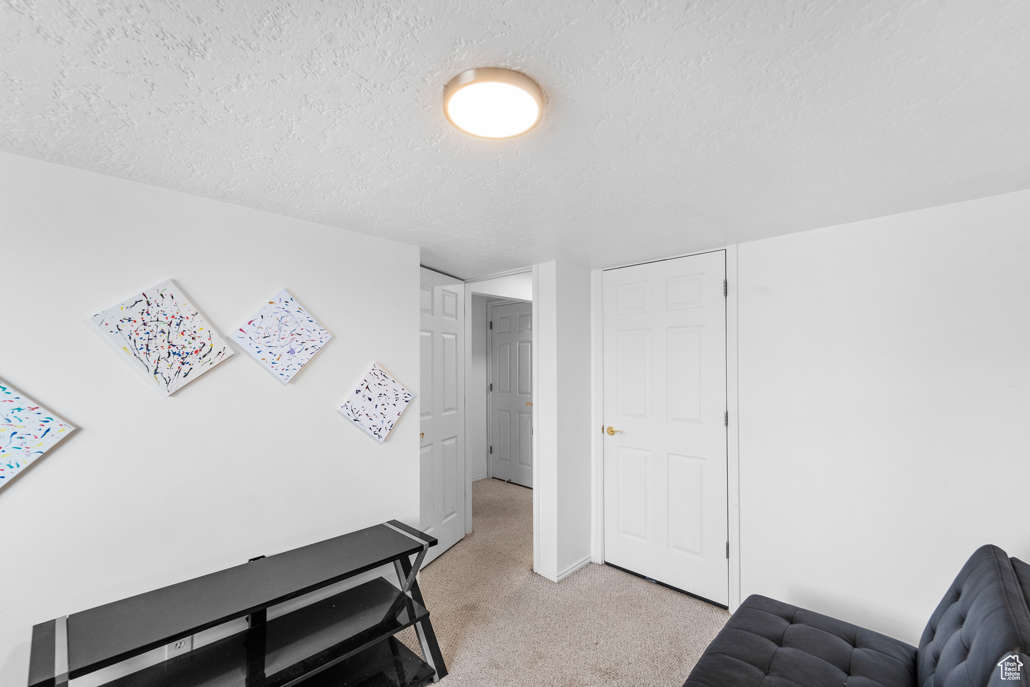 Living area with a textured ceiling and light colored carpet