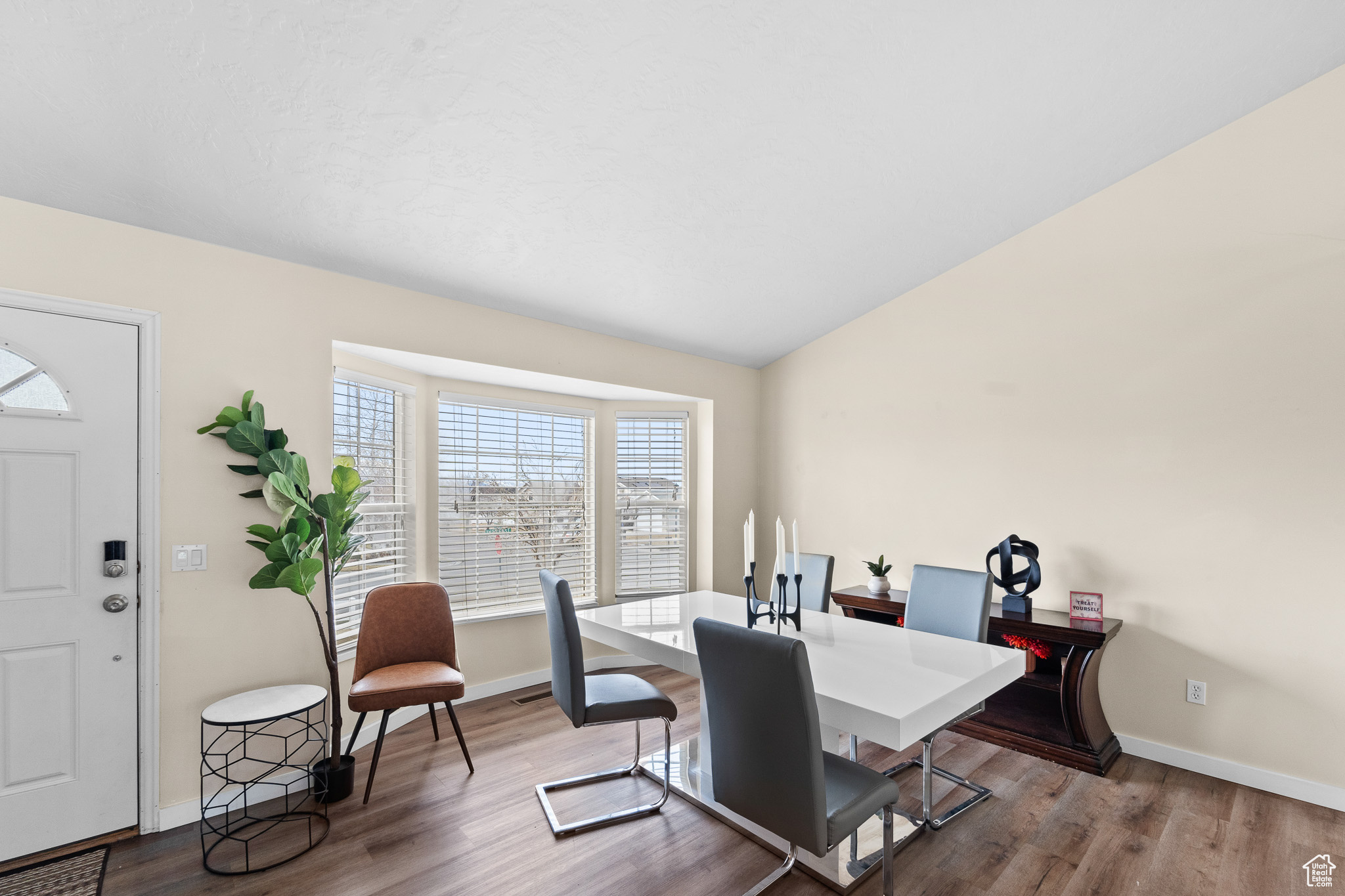 Dining area with light wood-style floors, lofted ceiling, and baseboards