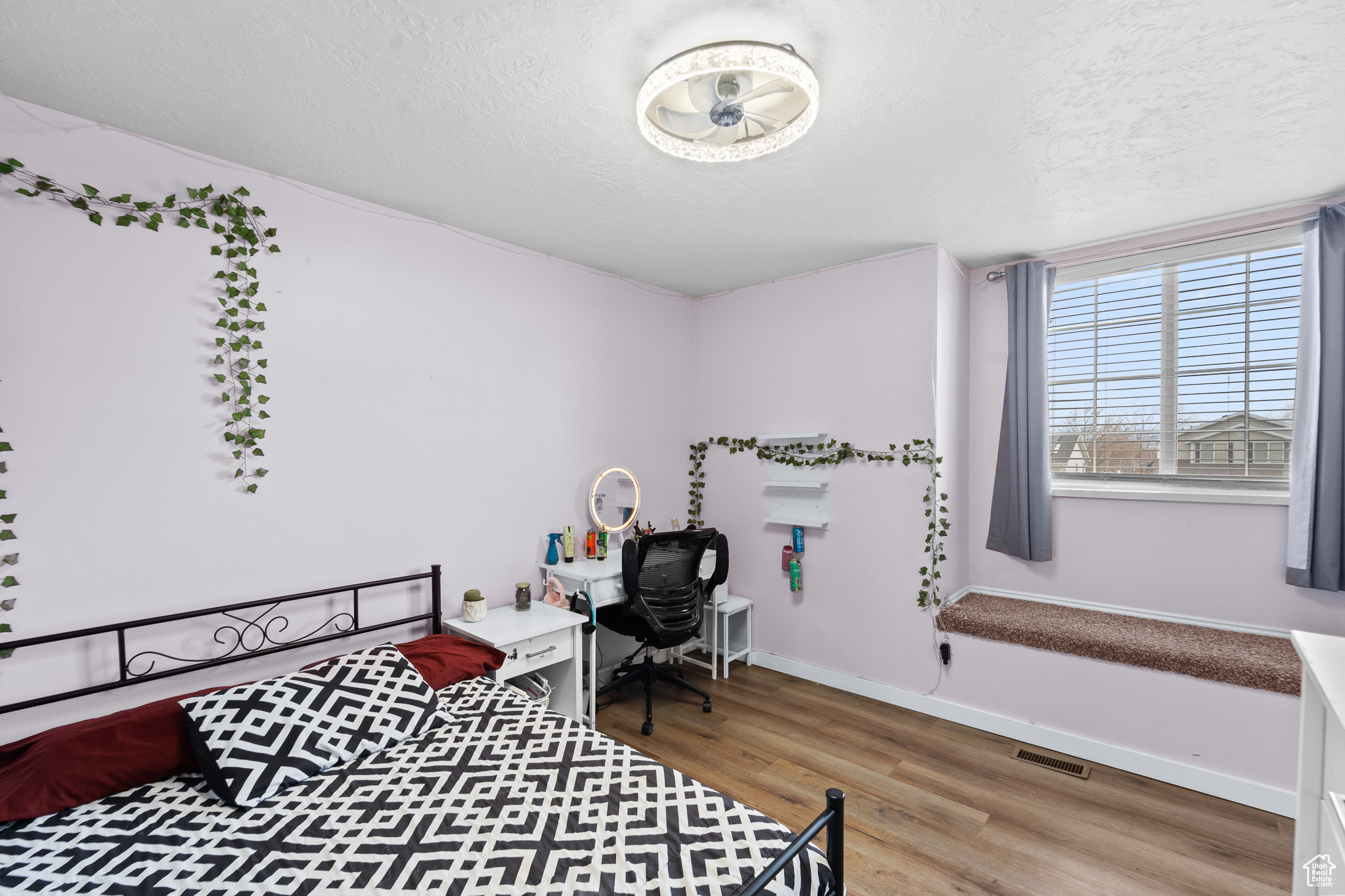 Bedroom featuring baseboards, a textured ceiling, visible vents, and wood finished floors