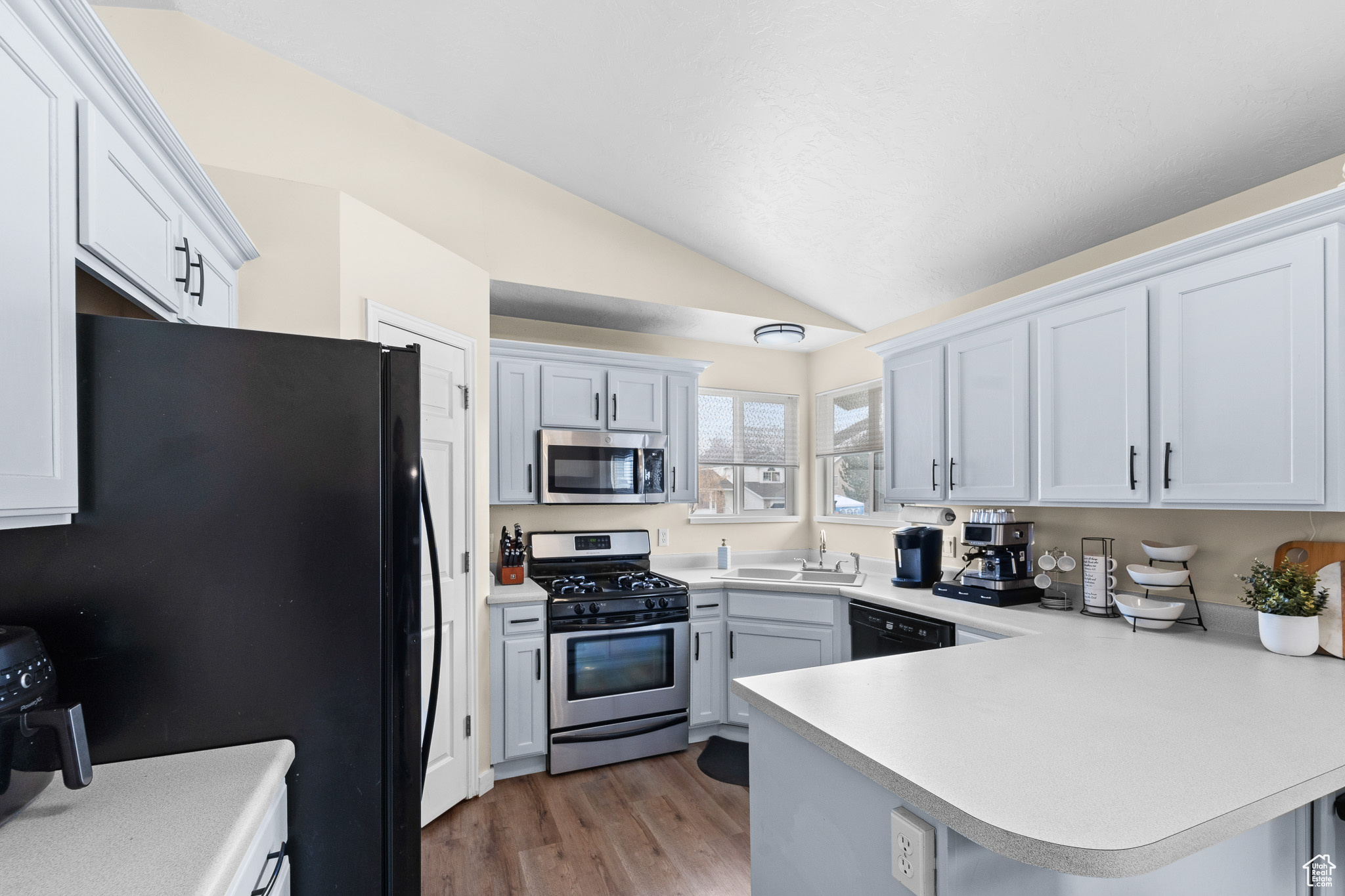 Kitchen featuring white cabinets, light countertops, a peninsula, and black appliances