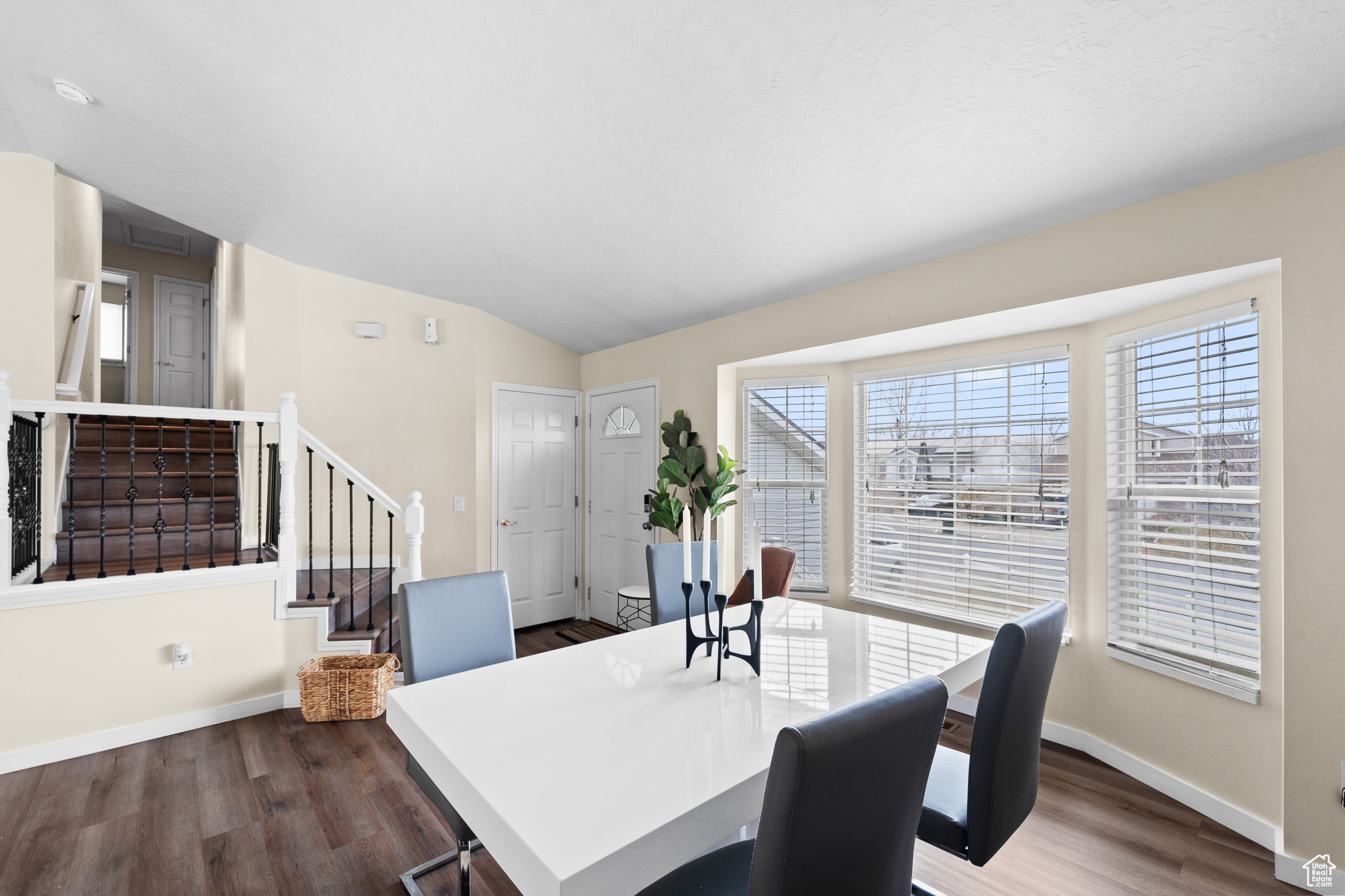 Dining room with lofted ceiling, stairway, baseboards, and dark wood-type flooring