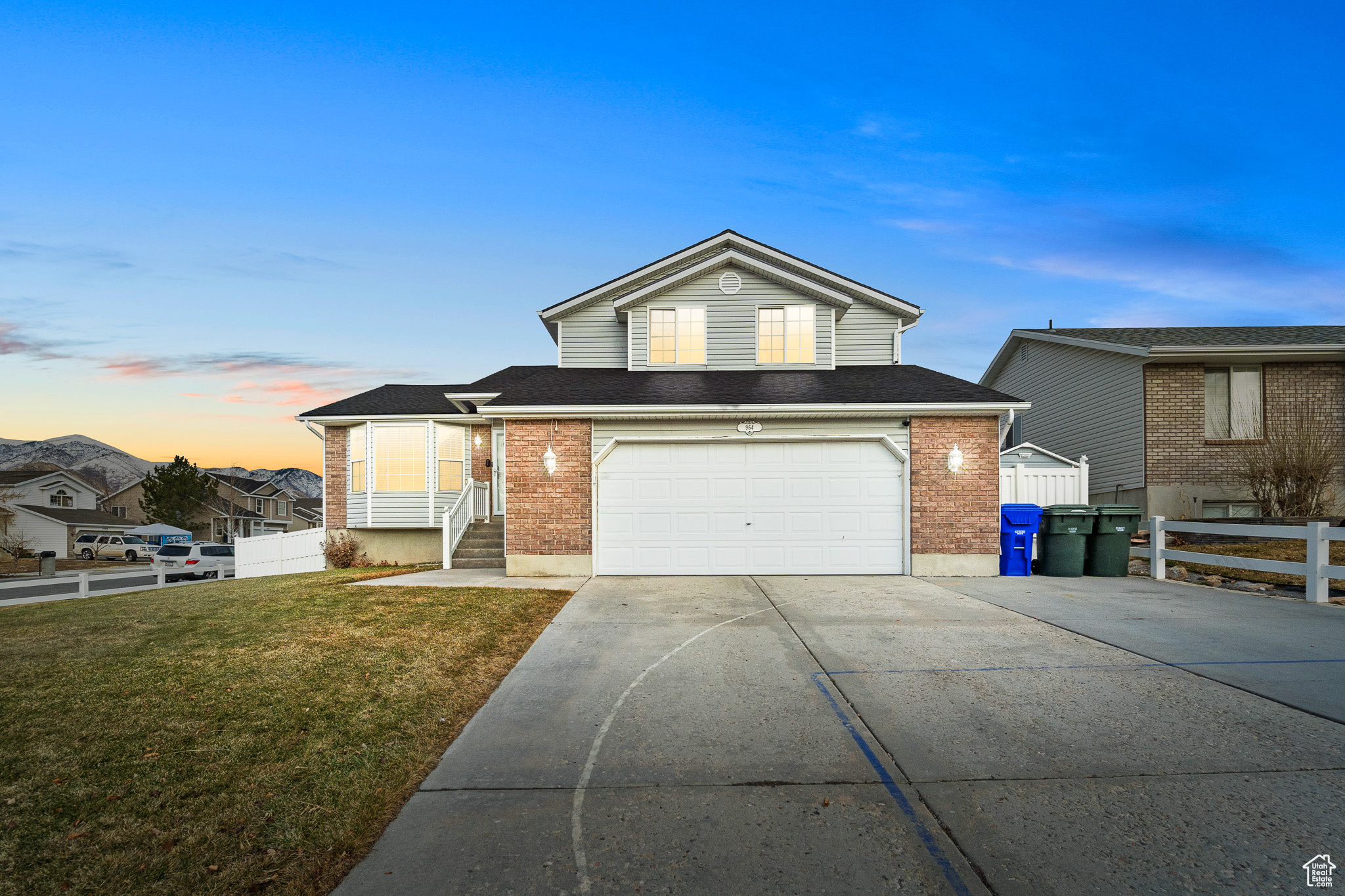 View of front facade with fence, a front lawn, concrete driveway, and brick siding