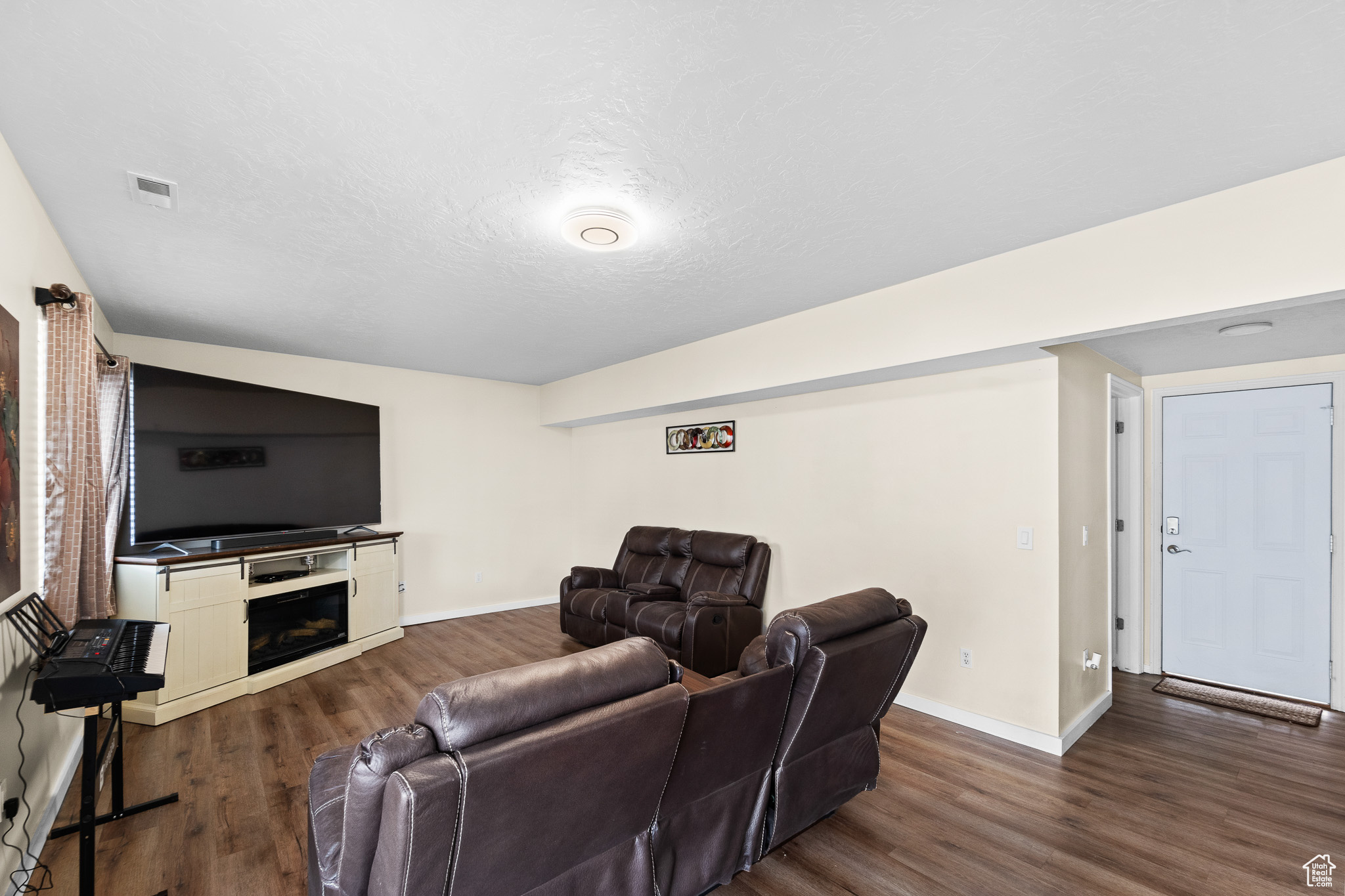 Living room with dark wood-style floors, a textured ceiling, a fireplace, and baseboards