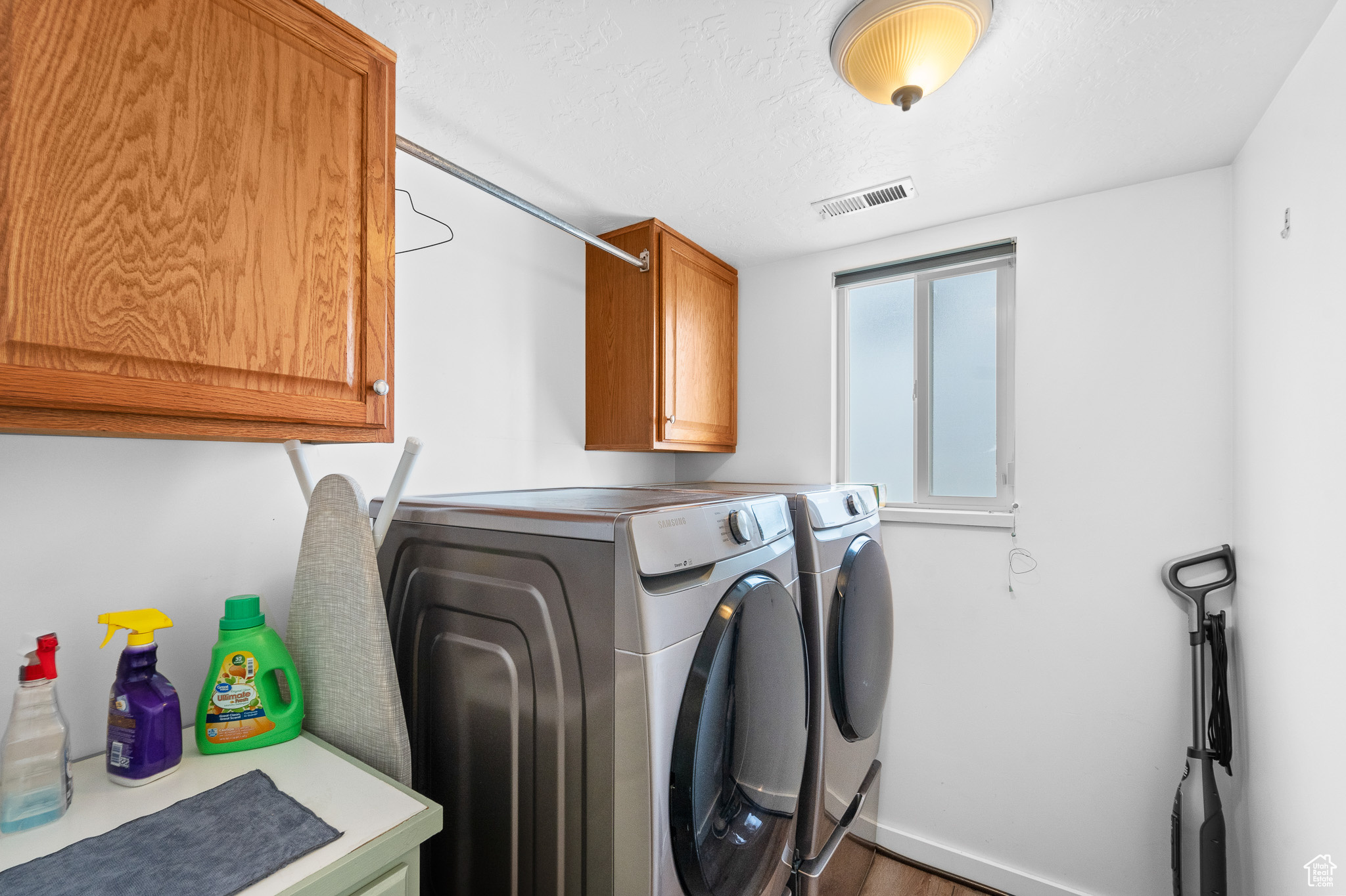 Washroom with cabinet space, visible vents, a textured ceiling, and independent washer and dryer