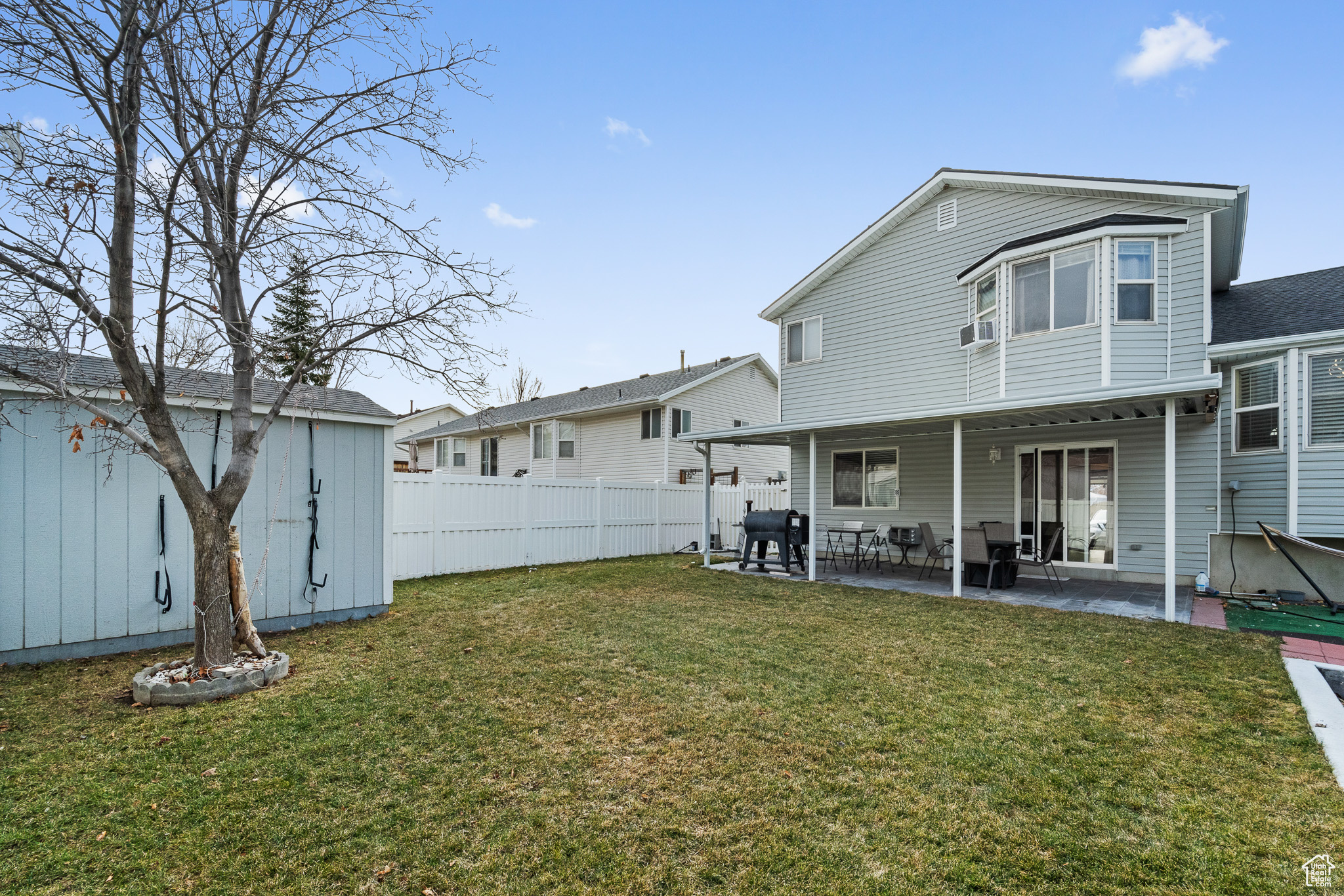 Rear view of property with a lawn, a patio area, and fence