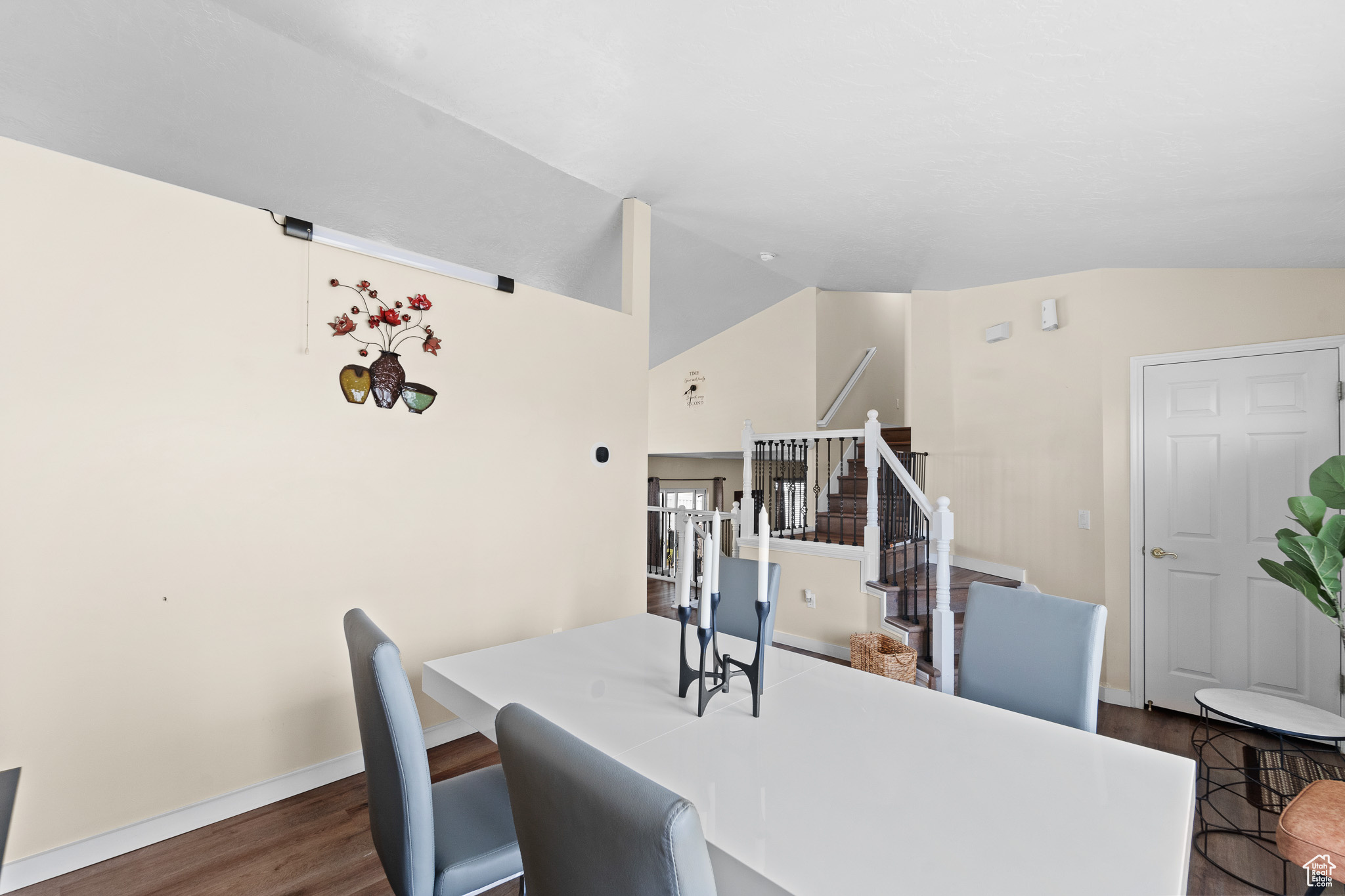 Dining room featuring dark wood-style floors, vaulted ceiling, stairway, and baseboards