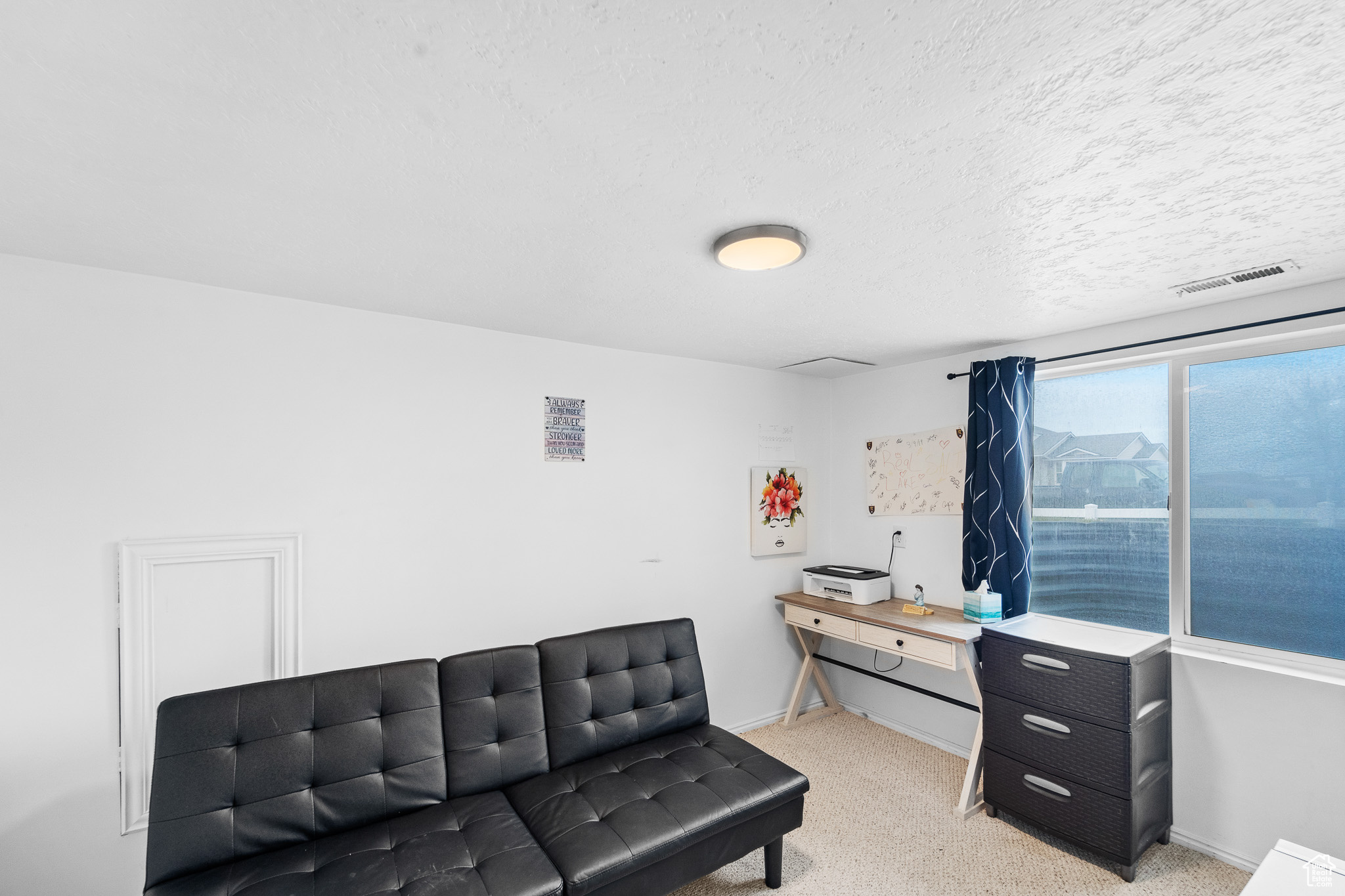 Living area featuring light carpet, baseboards, visible vents, and a textured ceiling