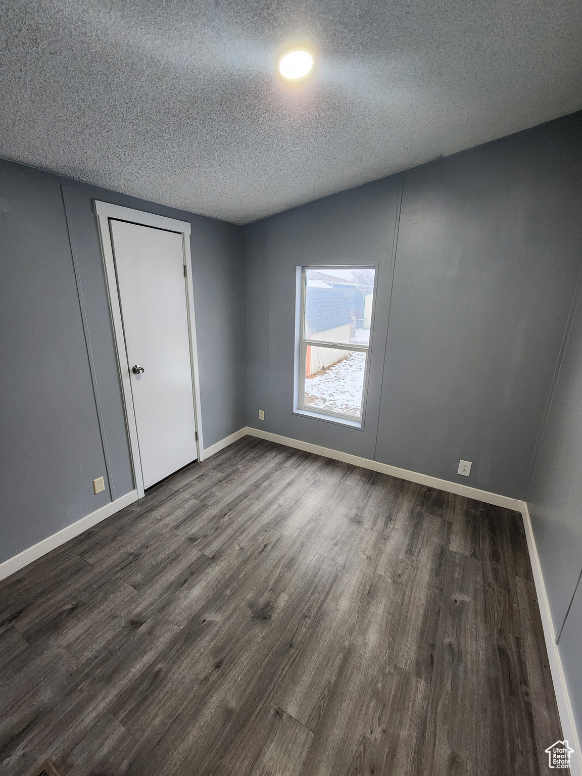 Spare room with dark wood finished floors, a textured ceiling, and baseboards