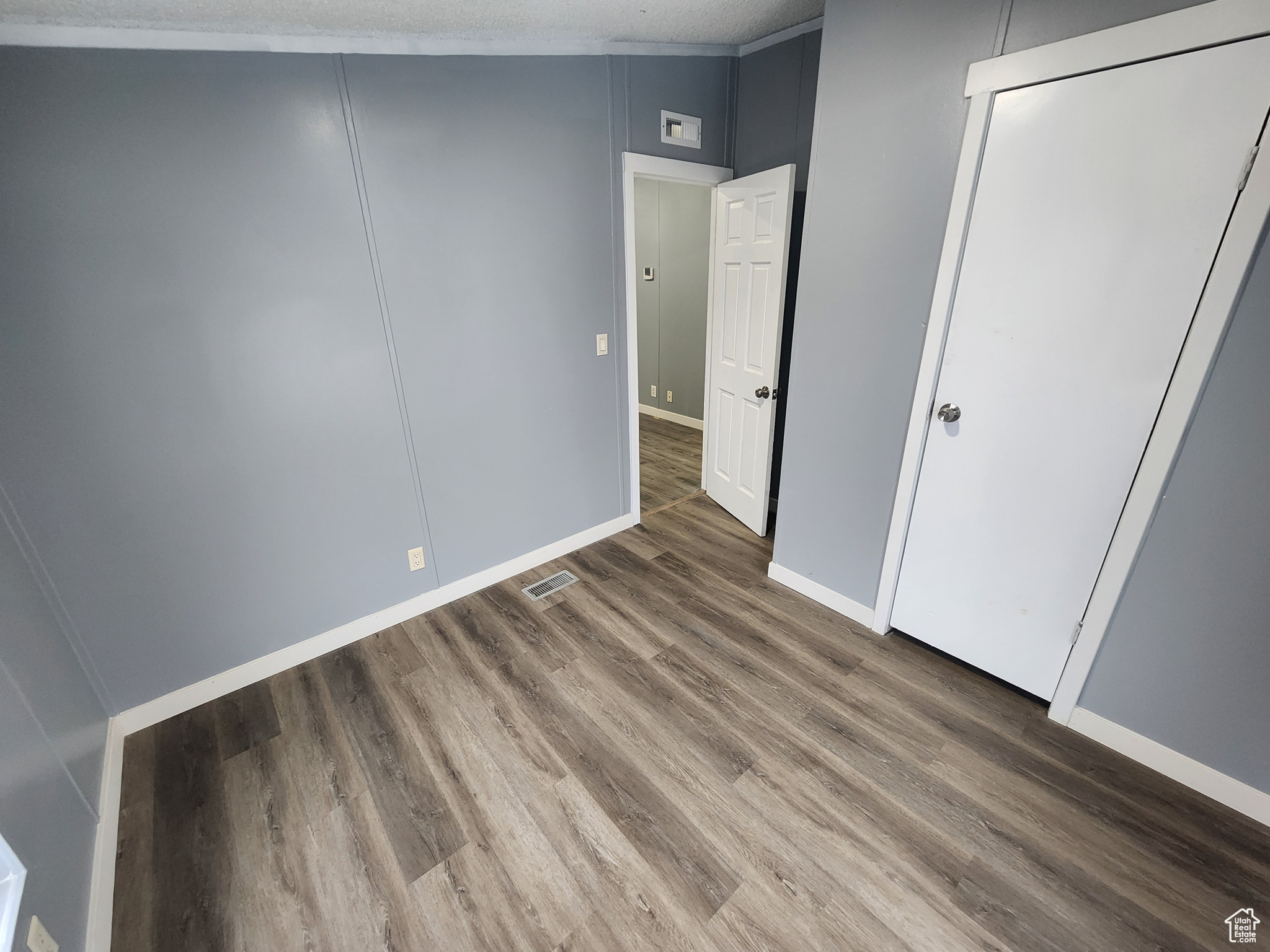 Unfurnished bedroom with dark wood finished floors, visible vents, and baseboards