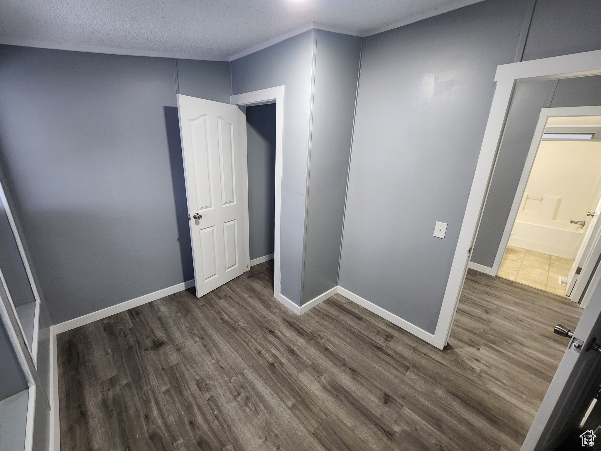 Unfurnished room with dark wood-style floors, baseboards, and a textured ceiling