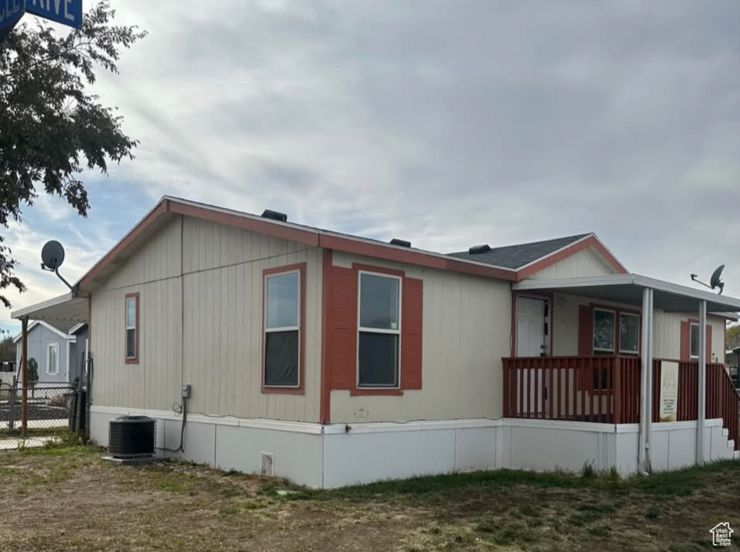 View of side of home featuring covered porch, fence, and central AC unit