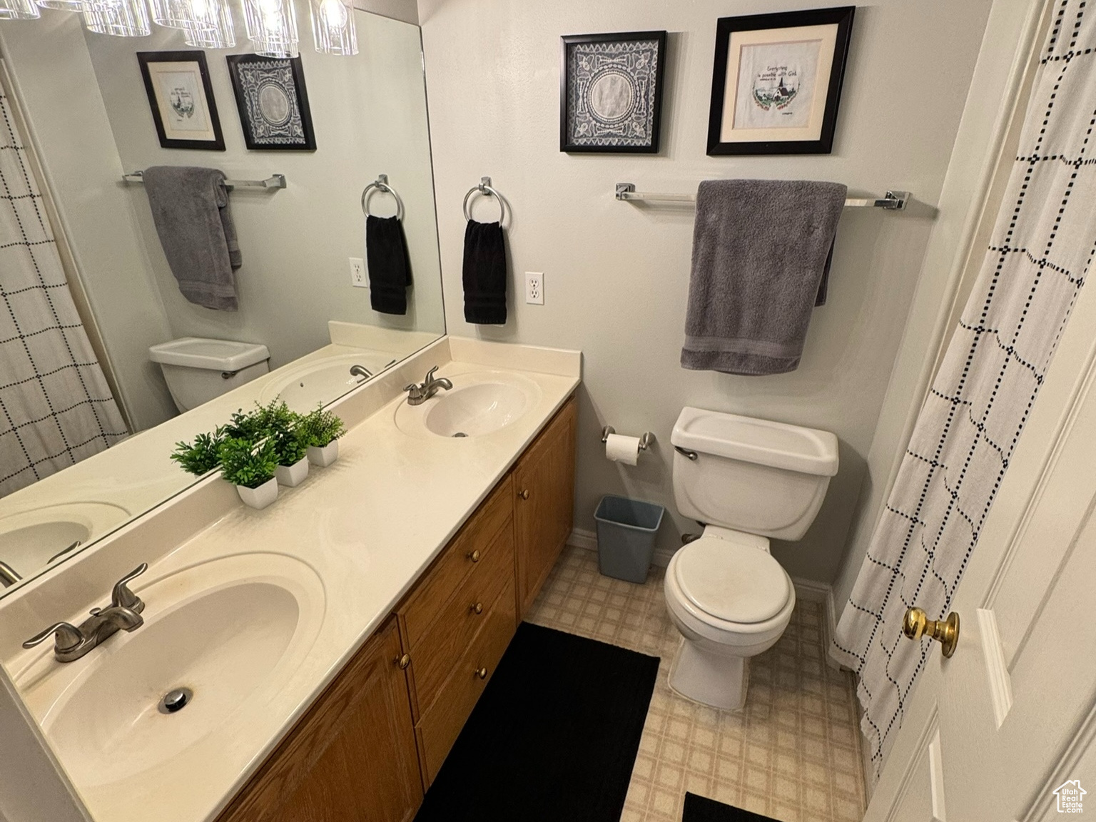 Full bathroom with double vanity, a sink, toilet, and baseboards