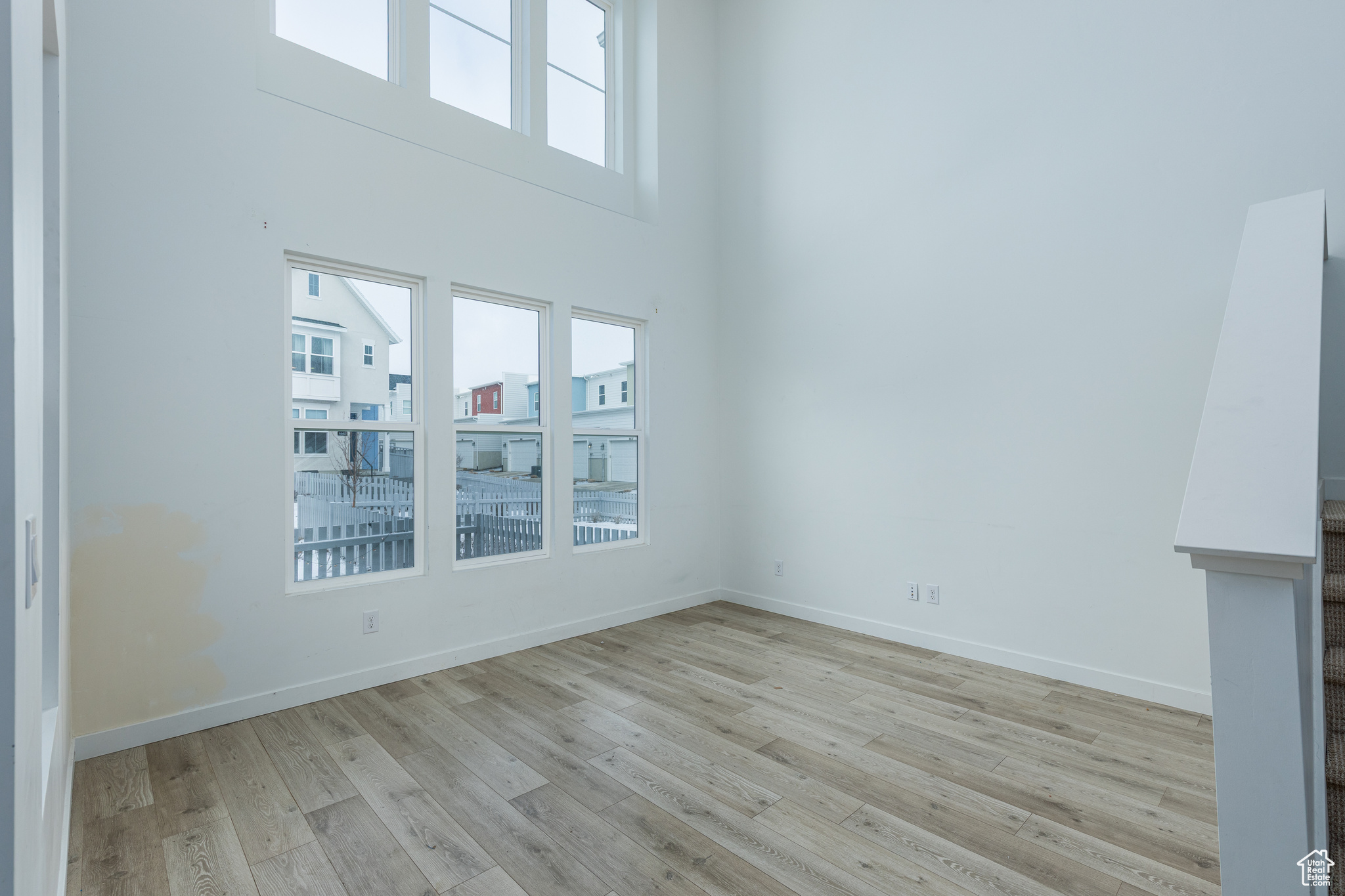 Empty room featuring plenty of natural light, light wood-style flooring, and baseboards