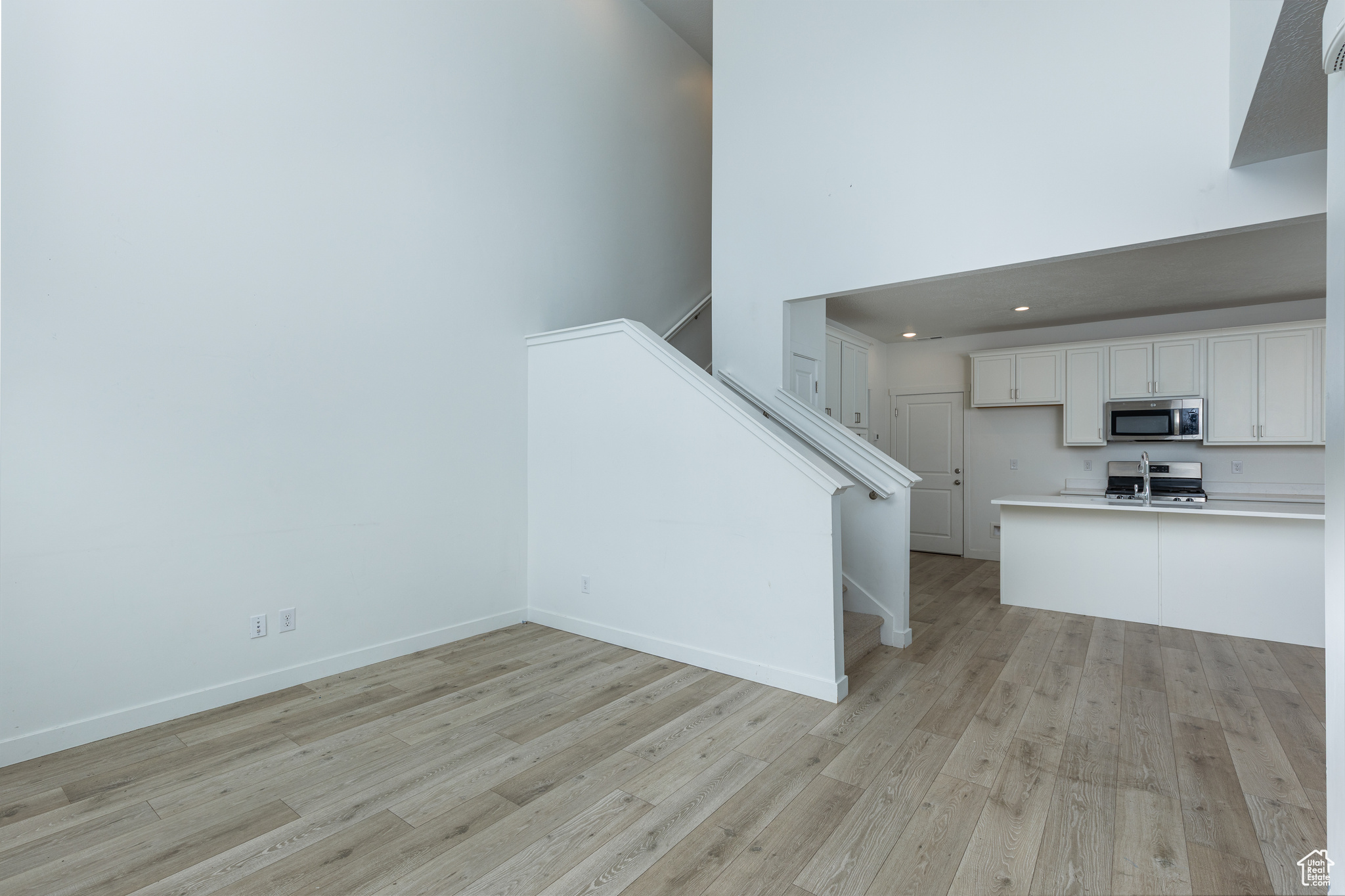 Kitchen featuring light countertops, appliances with stainless steel finishes, light wood-style floors, white cabinetry, and a peninsula