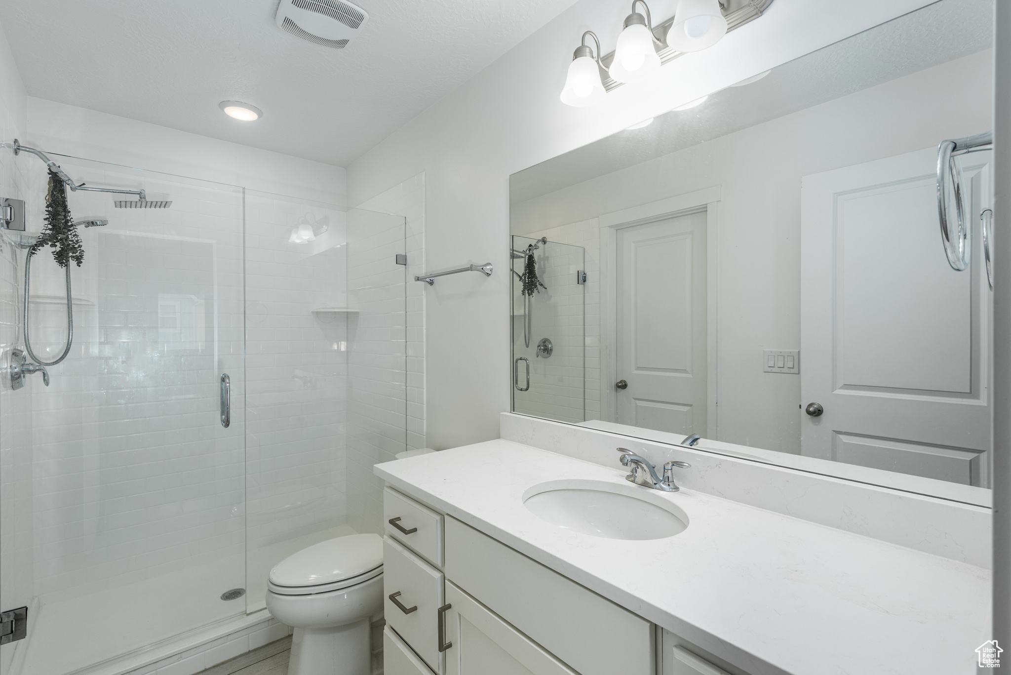 Bathroom with toilet, a stall shower, visible vents, and vanity
