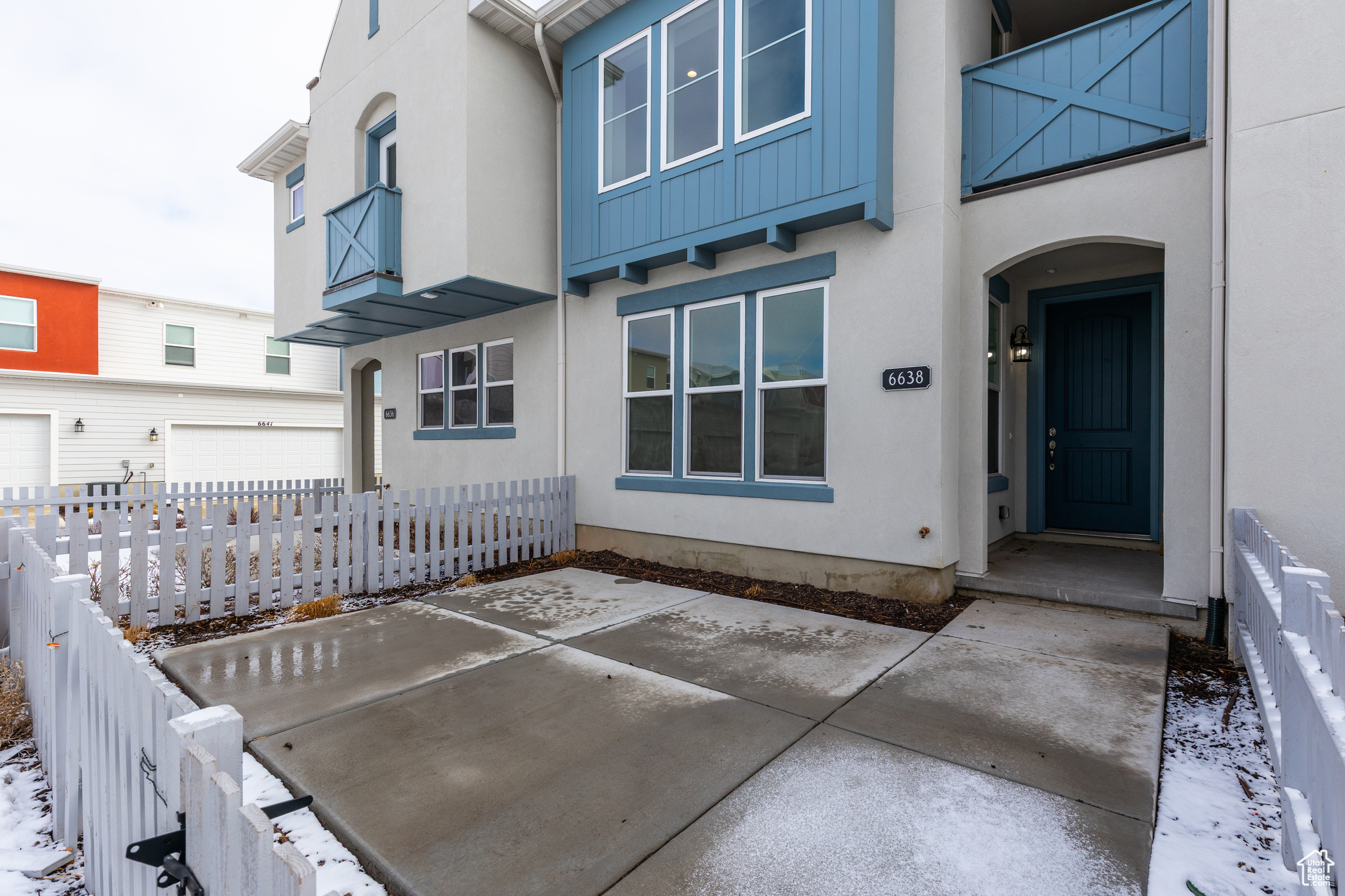 Snow covered property entrance featuring fence and stucco siding