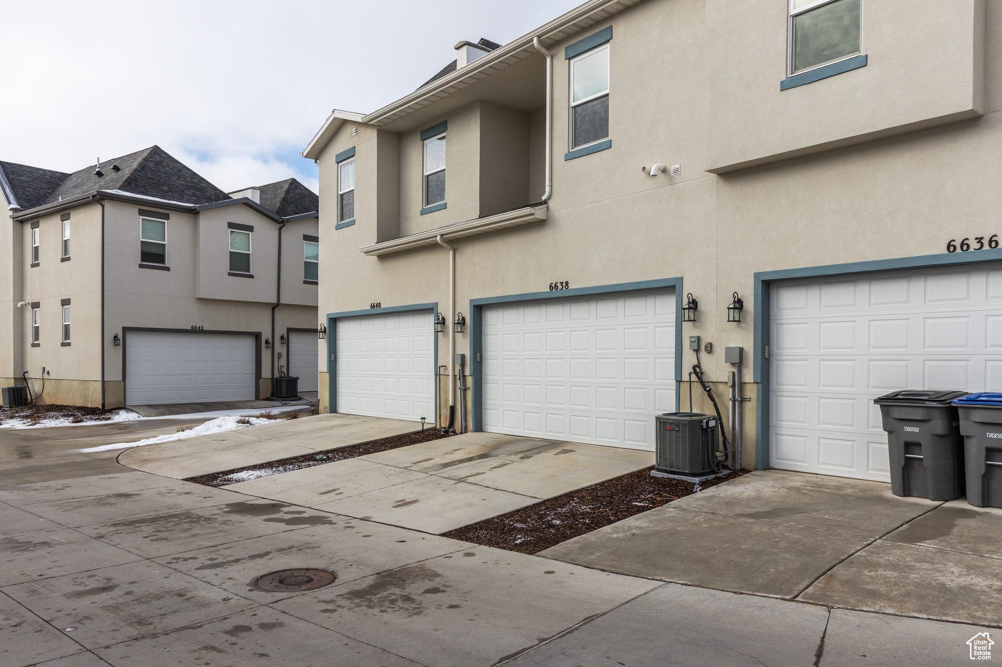 View of front facade featuring central air condition unit, an attached garage, and stucco siding