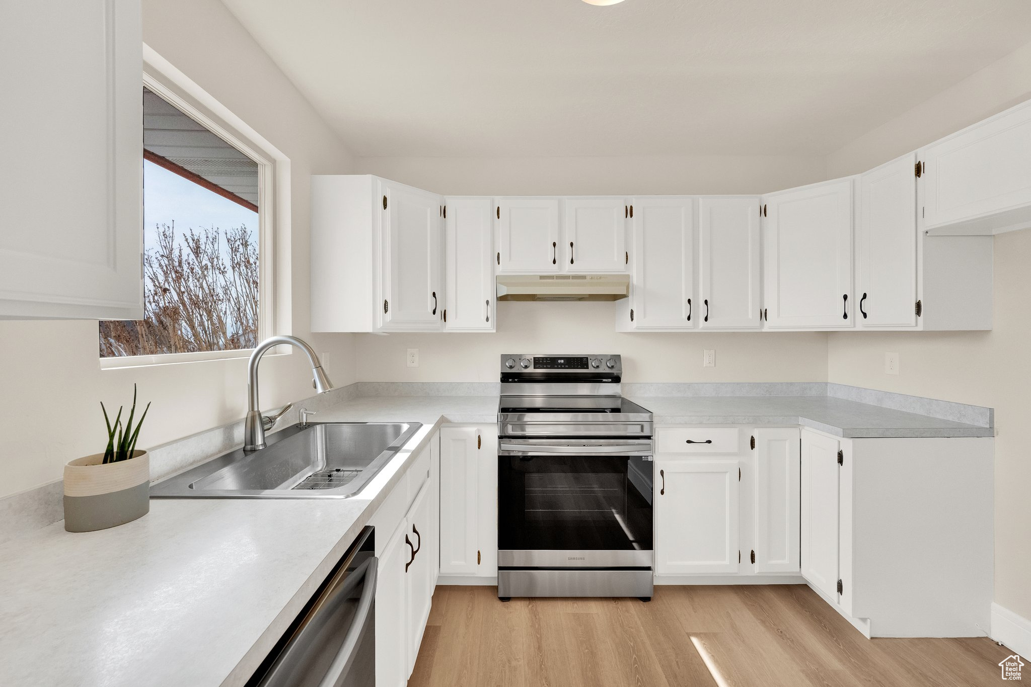 Kitchen featuring new sink, white cabinets, light countertops, and appliances with stainless steel finishes